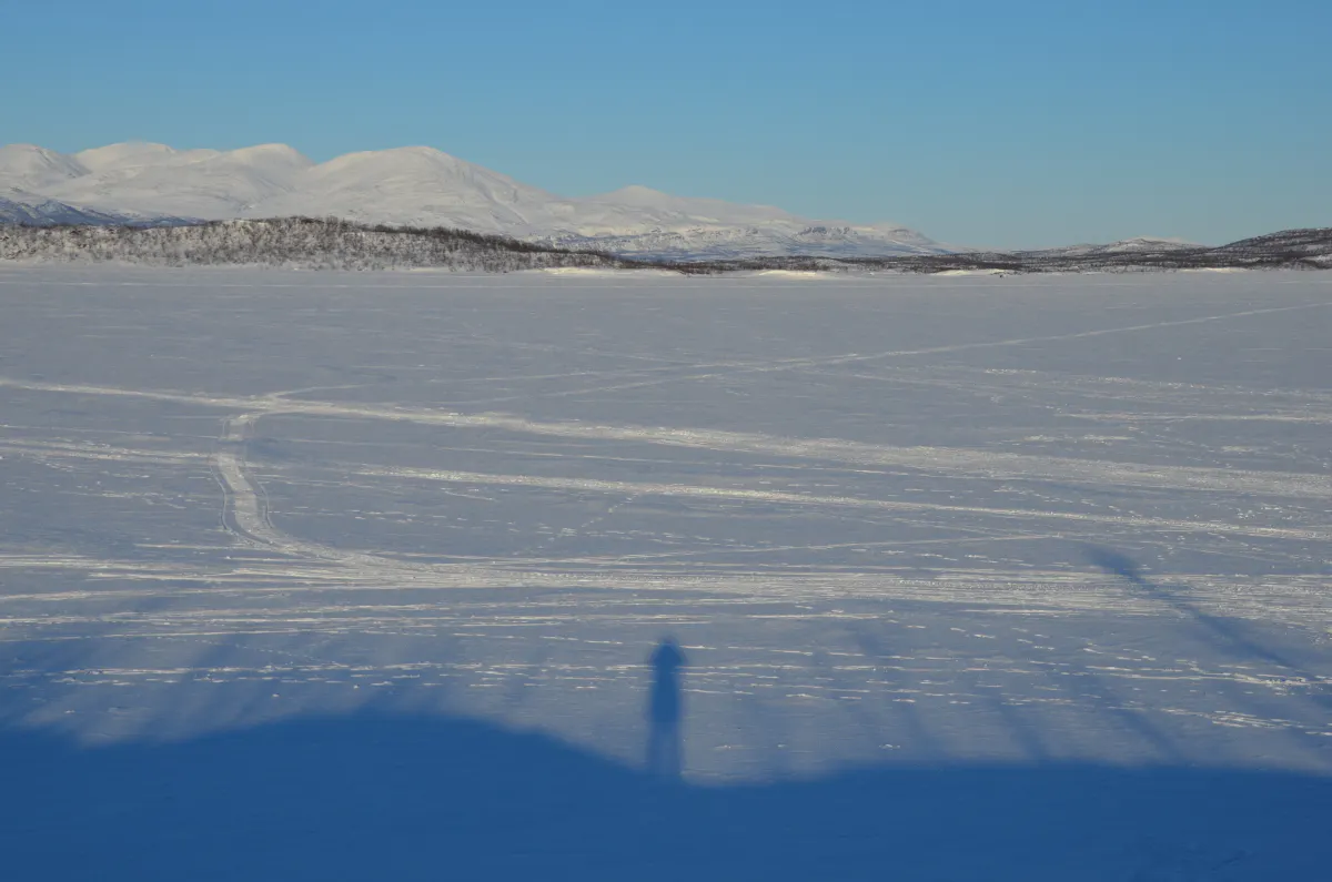 See mit Eis und Schnee drauf, im Hintergrund Berge