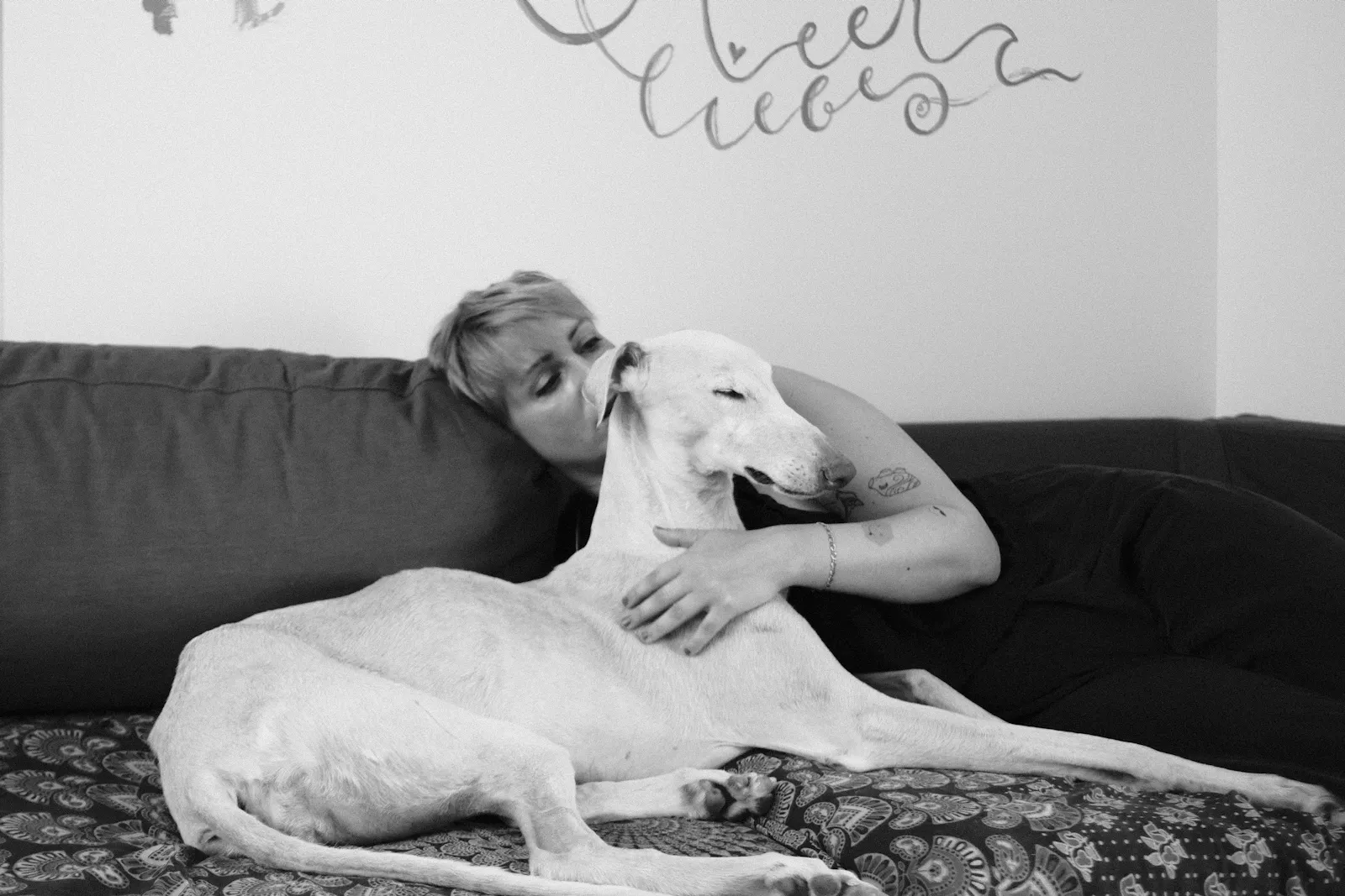 schwarz-weißes foto, duna liegt auf der couch, bianca umarmt sie. die foto credits liegen bei (c) Anna Maria Schmelzer