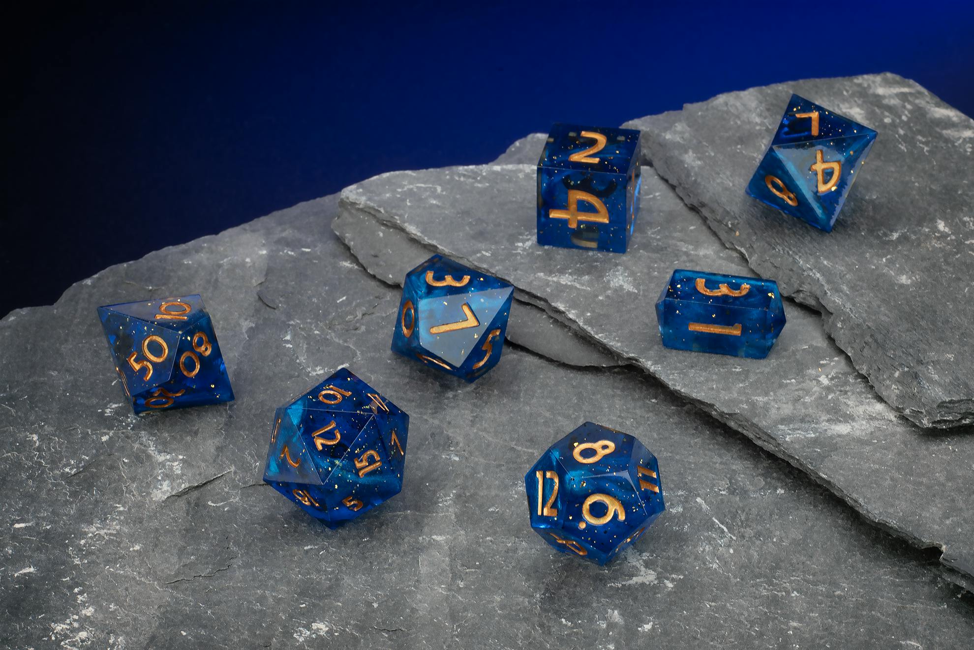 Tiefblaues, transparentes Polyeder-Würfelset mit feinen Glitzerpartikeln und goldenen Zahlen.