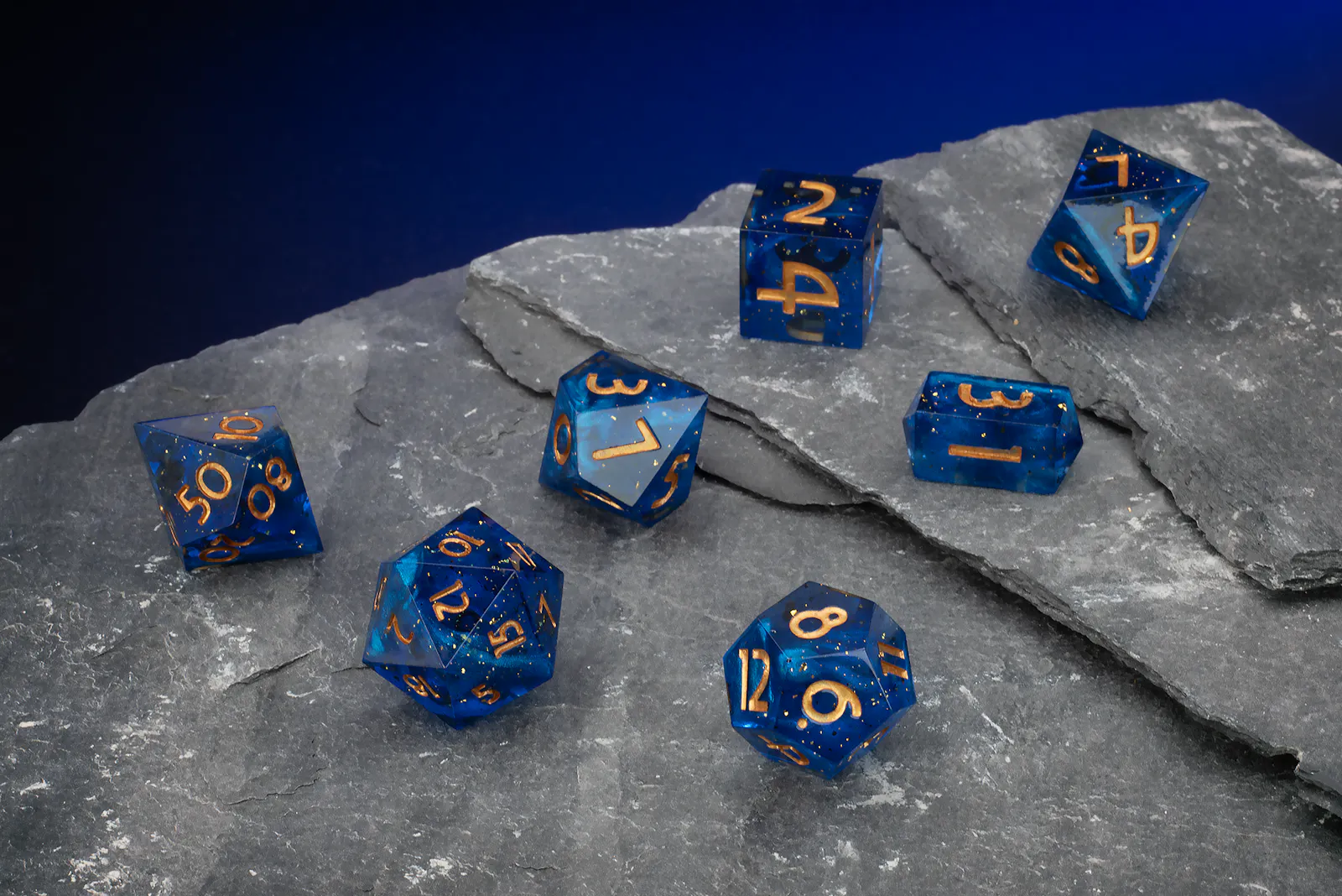 Tiefblaues, transparentes Polyeder-Würfelset mit feinen Glitzerpartikeln und goldenen Zahlen.