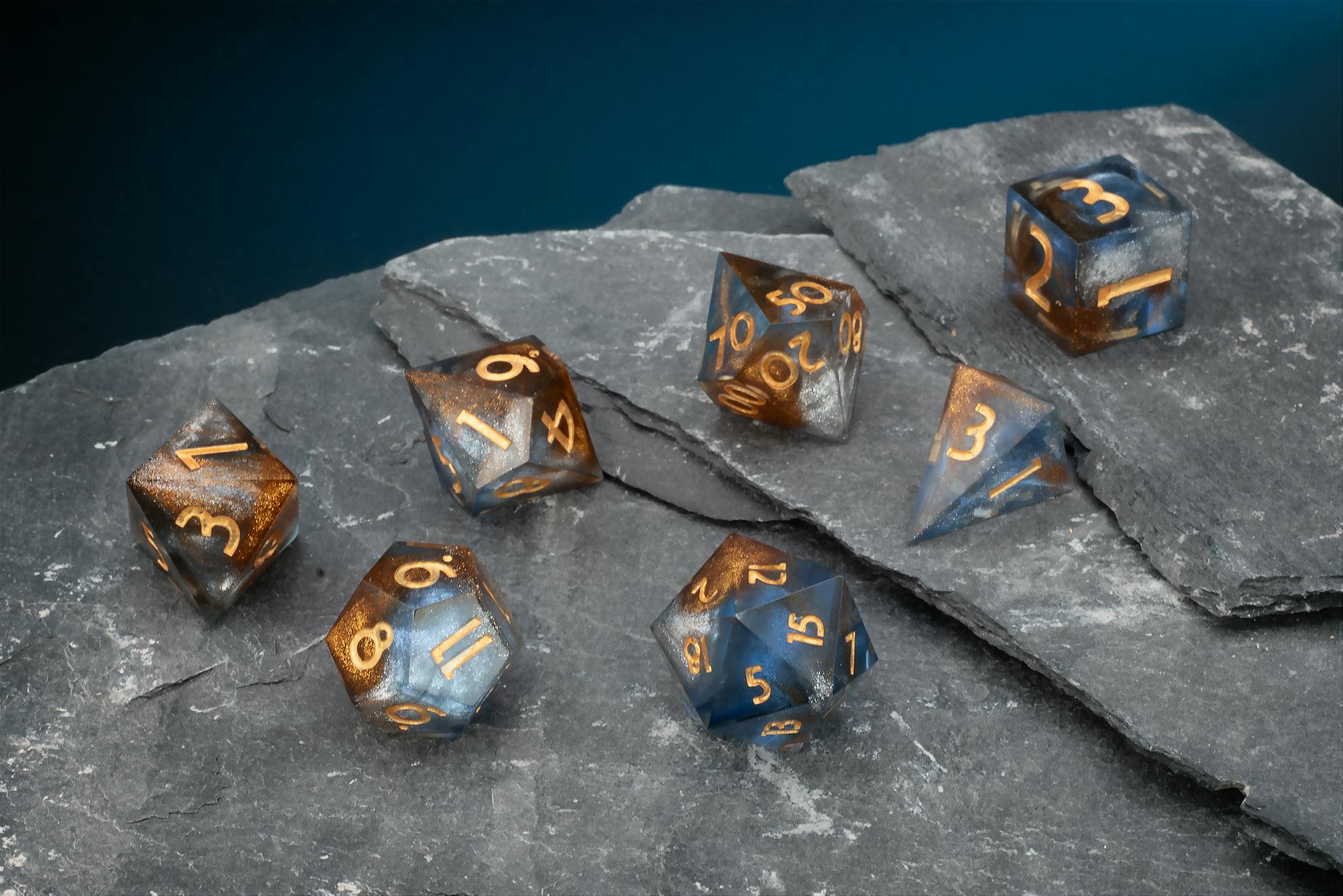 Blau-grau-transparentes Polyeder-Würfelset mit goldenen Zahlen und feinen Glitzerpartikeln.