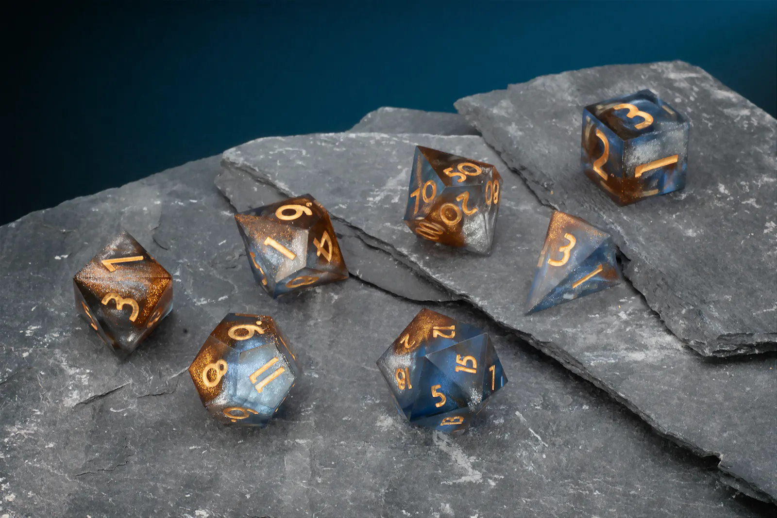 Blau-grau-transparentes Polyeder-Würfelset mit goldenen Zahlen und feinen Glitzerpartikeln.