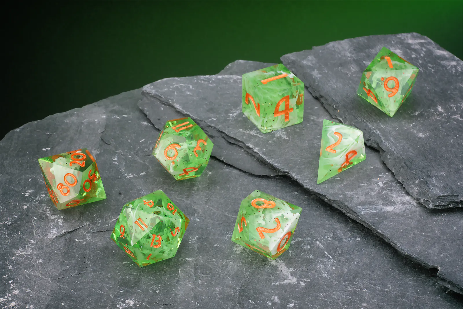 Grün-transparentes Polyeder-Würfelset mit feinen Einschlüssen und orangefarbenen Zahlen.