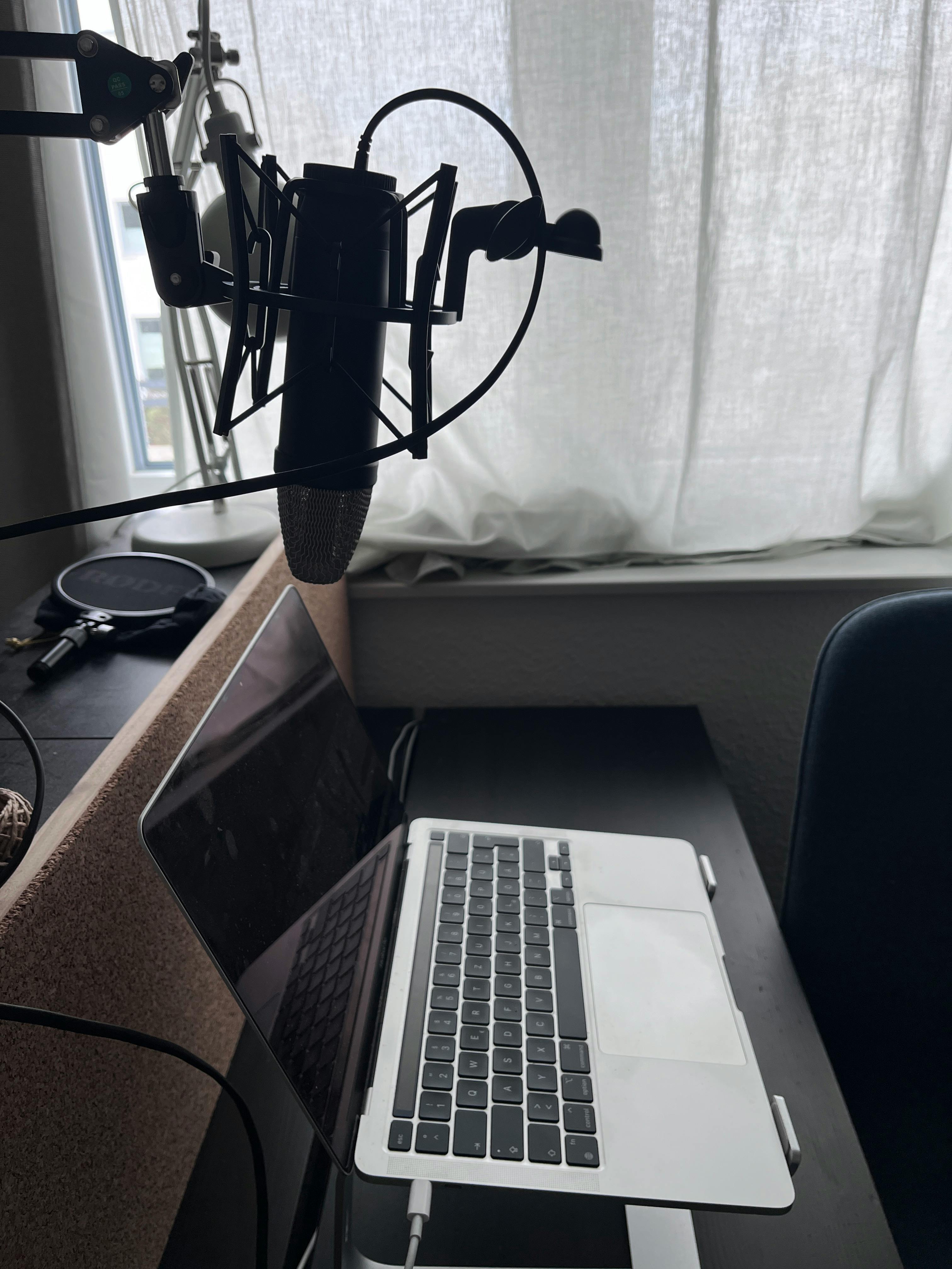 Ein Laptop steht auf dem Tisch, darüber hängt ein Profi-Mikrofon.