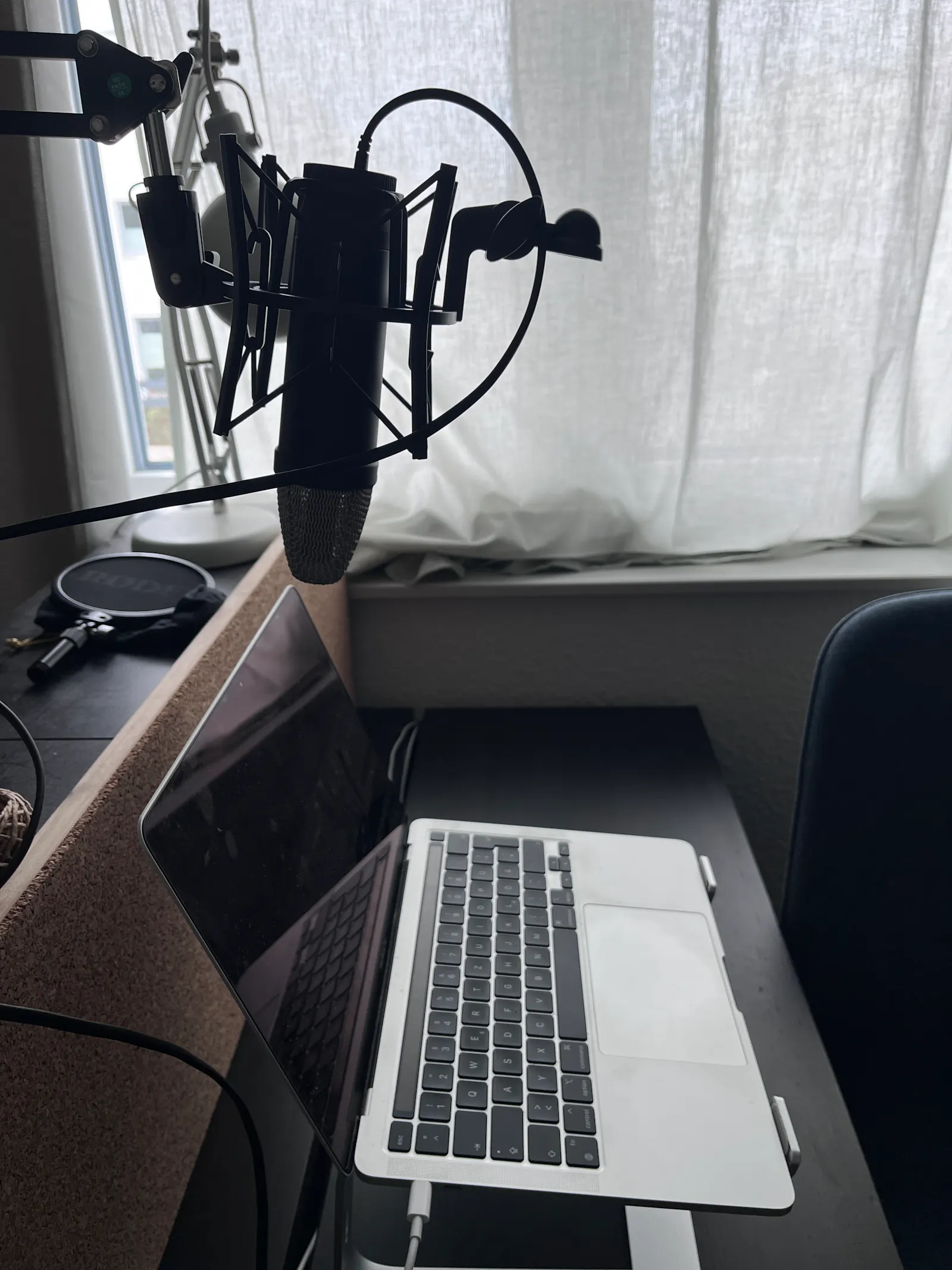 Ein Laptop steht auf dem Tisch, darüber hängt ein Profi-Mikrofon.