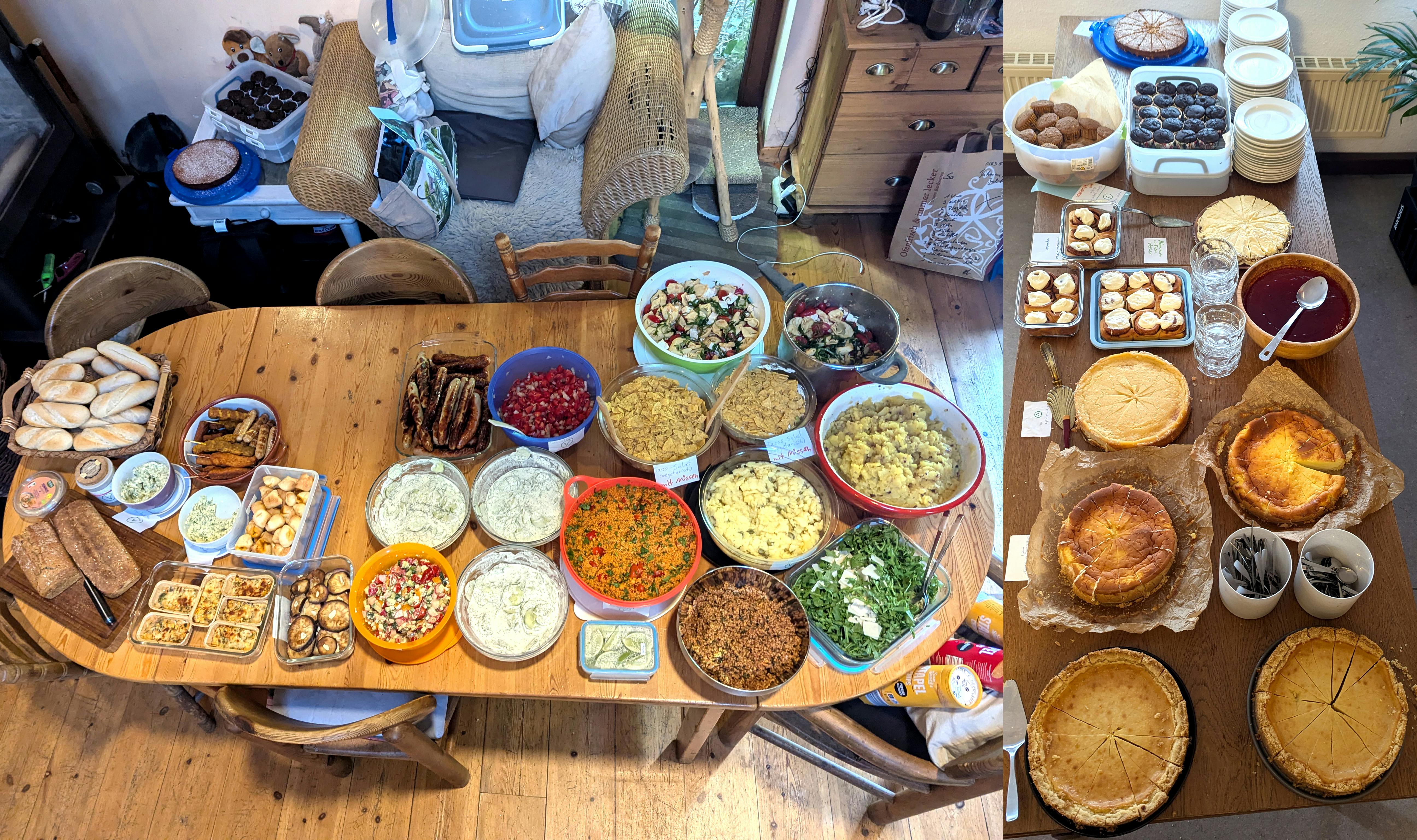 Zwei Tische voller Speisen beim Potluck-Buffet des Sommertreffens: Links ein großer Holztisch, dicht belegt mit herzhaften Gerichten – darunter verschiedene Salate, Dips, Aufläufe, Brote, gegrilltes Gemüse und bunte Schüsseln mit Getreide- und Hülsenfrüchtegerichten. Rechts ein weiterer Tisch mit dem süßen Buffet: mehrere Kuchen, Torten, Muffins, Zimtschnecken und andere Backwaren, dazu Teller und Besteck.