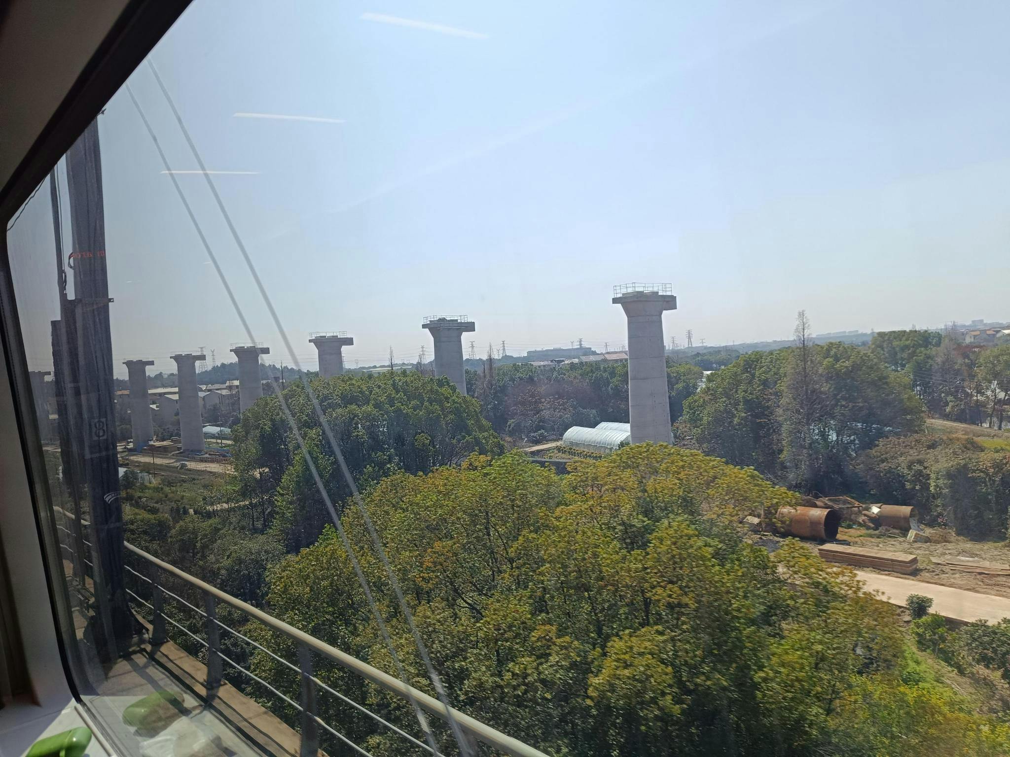 Riesige Betonpfeiler in der Landschaft, aus dem Zugfenster fotografiert.