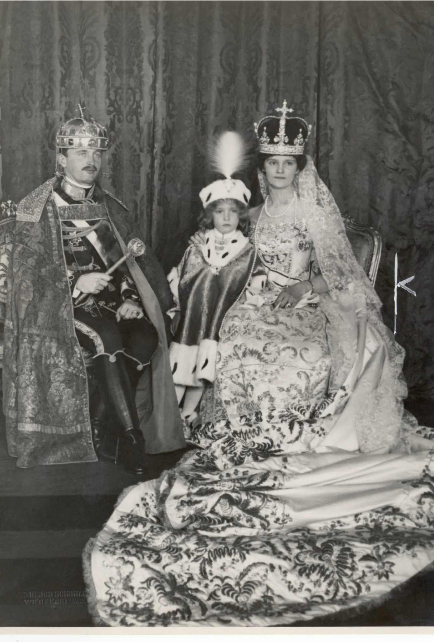 Das Bild zeigt Kaiser Karl I. zusammen mit seiner Frau Zita und seinem Sohn Otto. Die Aufnahme ist schwarz-weiß und stammt aus dem Jahr 1916.