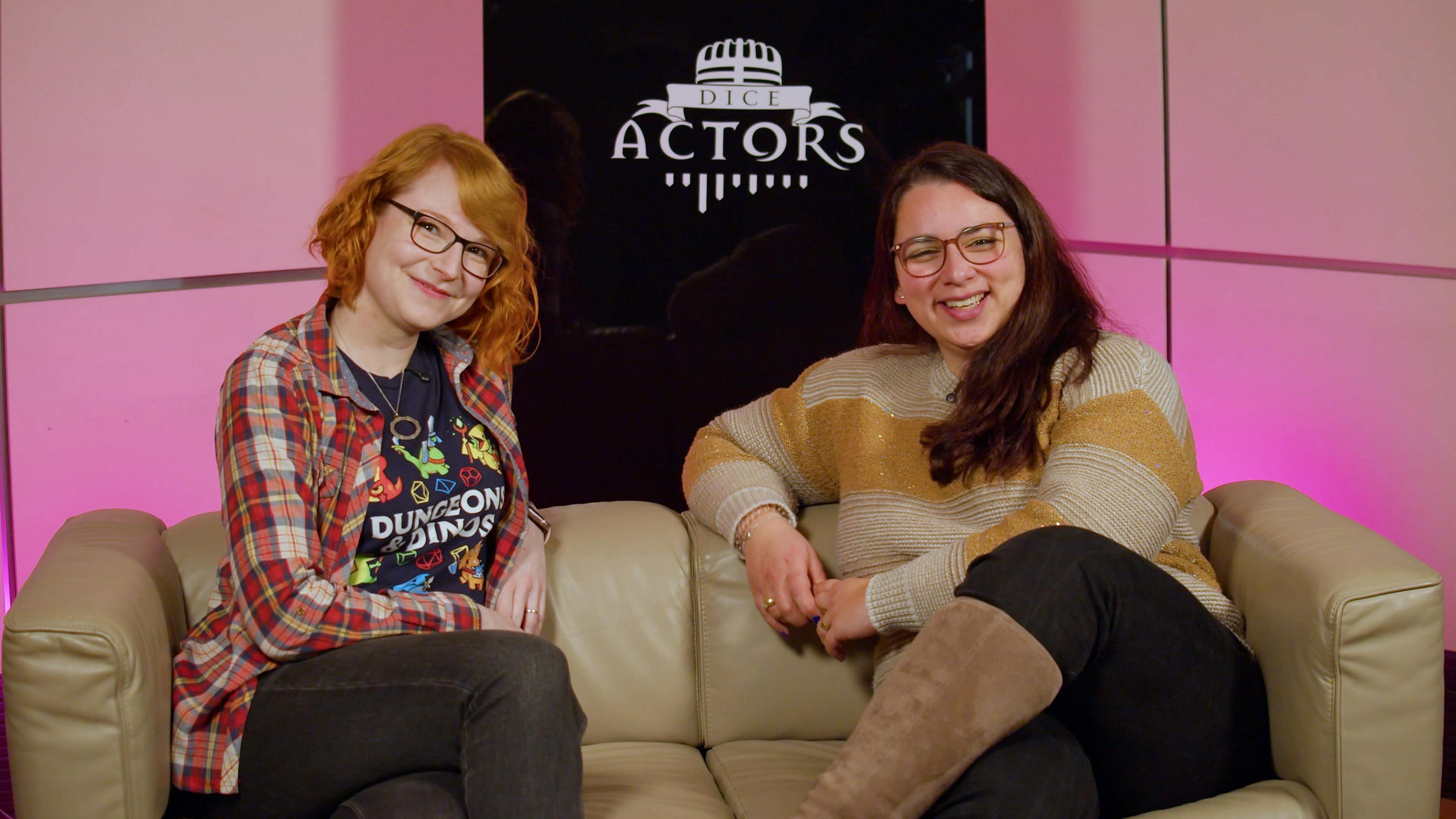 Stephie und Aylin sitzen glücklich auf einem Sofa, dahinter steht "Dice Actors" auf einer schwarzen Glasplatte.