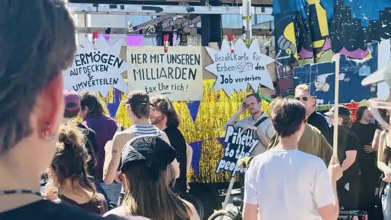 [Demoschilder und -teilnehmende am 1. Mai in Hamburg bei der Demo "Wer hat, der gibt"]