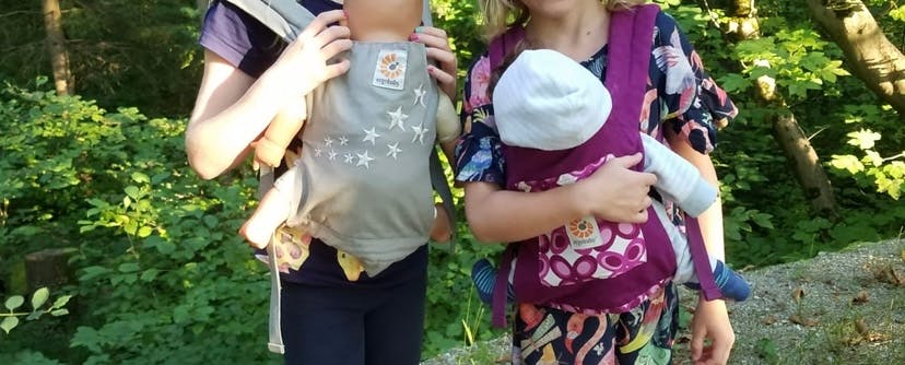 Zwei Mädchen mit Puppen in der Trage