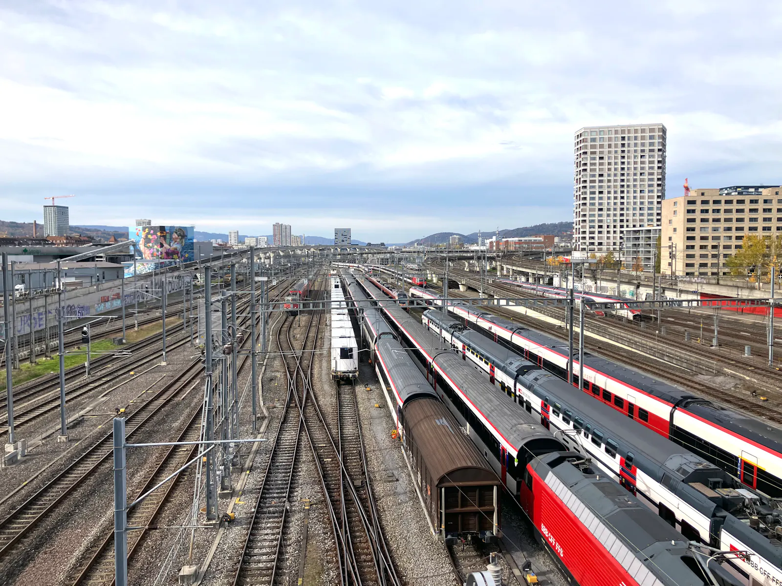 Gleisfeld zwischen Bahnhof Hardbrücke und Bahnhof Altstetten. Es stehen Züge auf den Gleisen. Im Hintergrund sind Hochhäuser zu sehen.