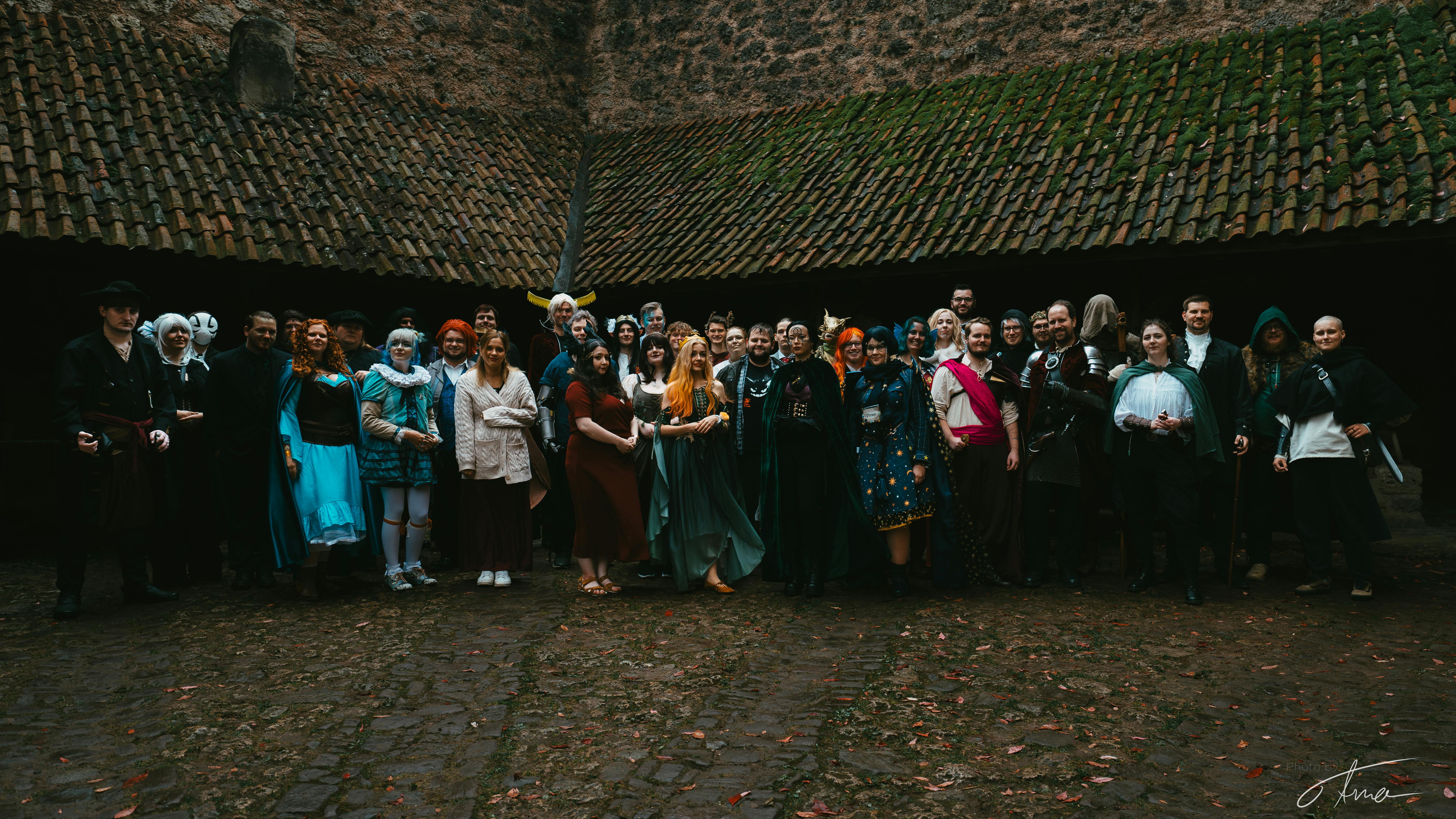 Eine große Gruppe Menschen, gekleidet in Fantasy-Gewandung, im Innenhof einer Burg.