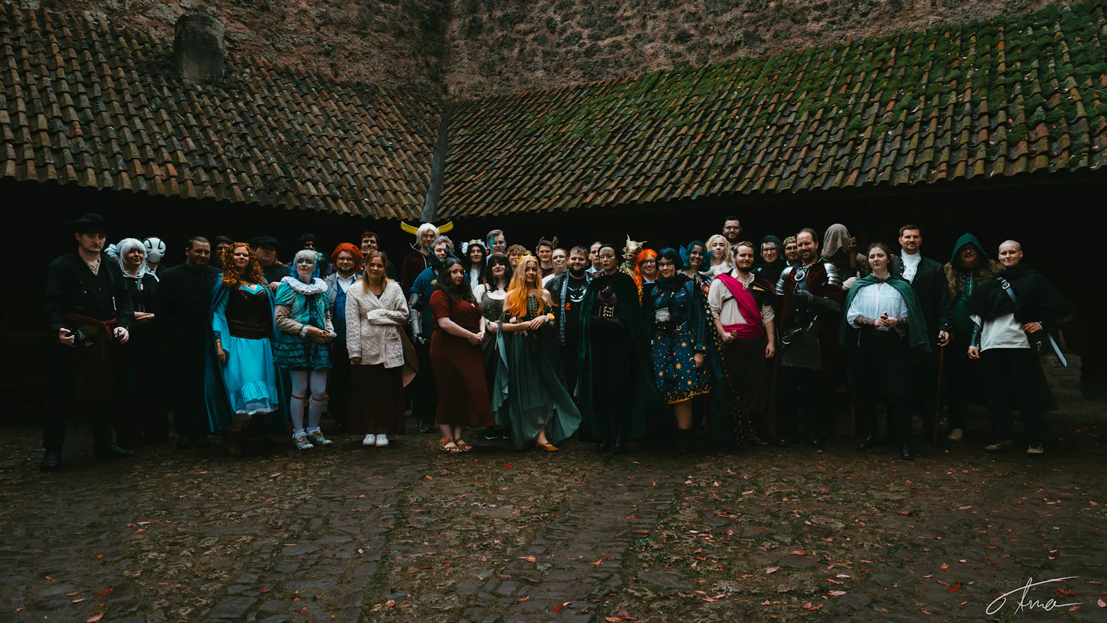 Eine große Gruppe Menschen, gekleidet in Fantasy-Gewandung, im Innenhof einer Burg.