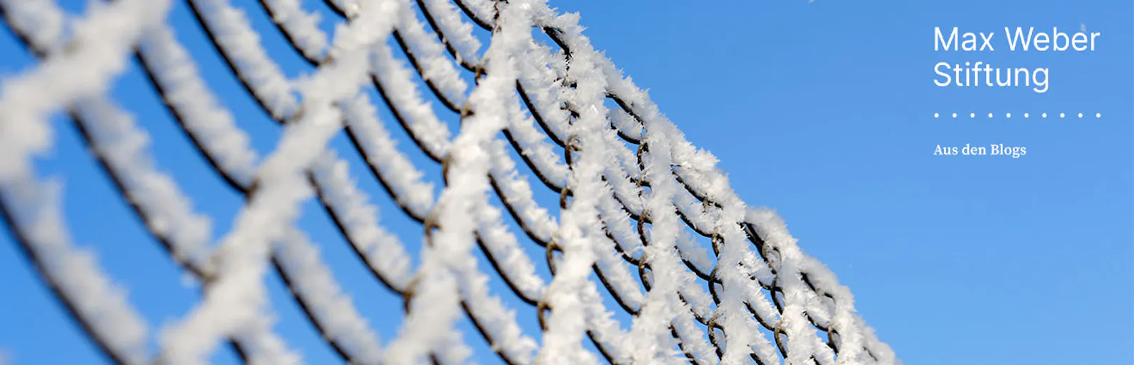 Frost bedeckter Zaun vor blauem Himmel