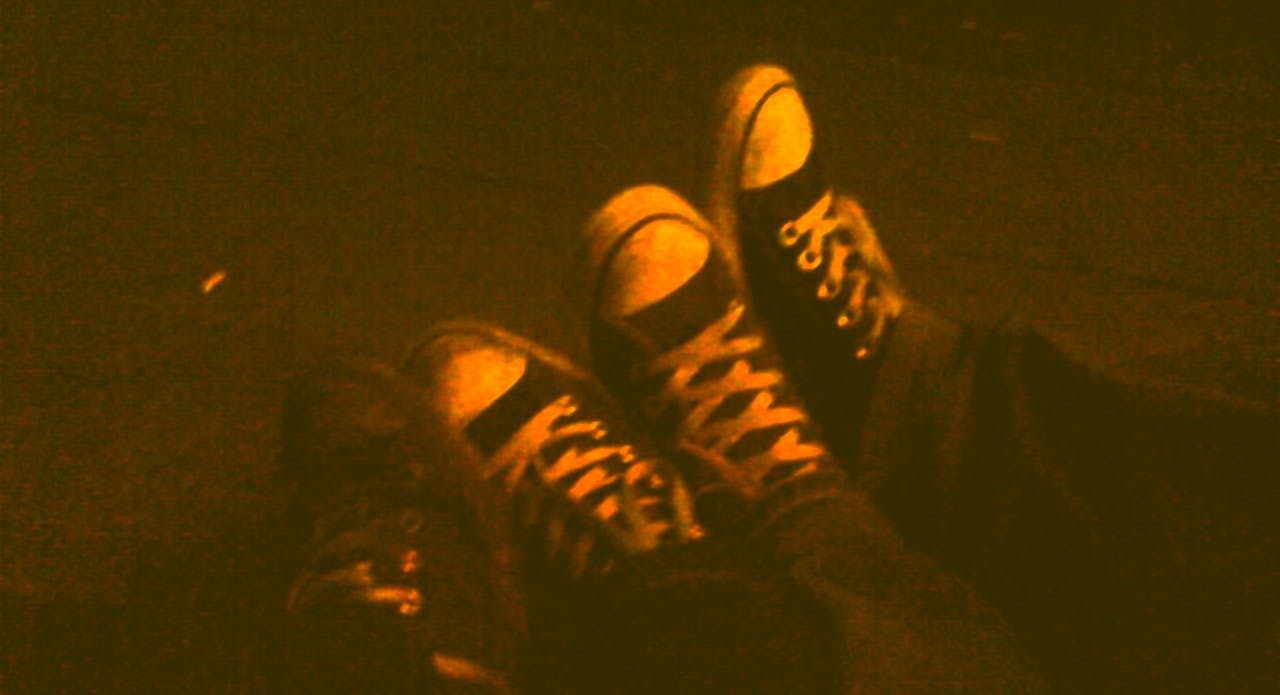 Dunkles Foto, Nacht, vier Füße in Converse Chucks aneinander gelehnt.