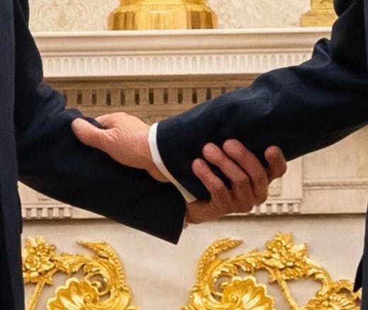 Merz und Trump halten Handgelenke in Nahaufnahme