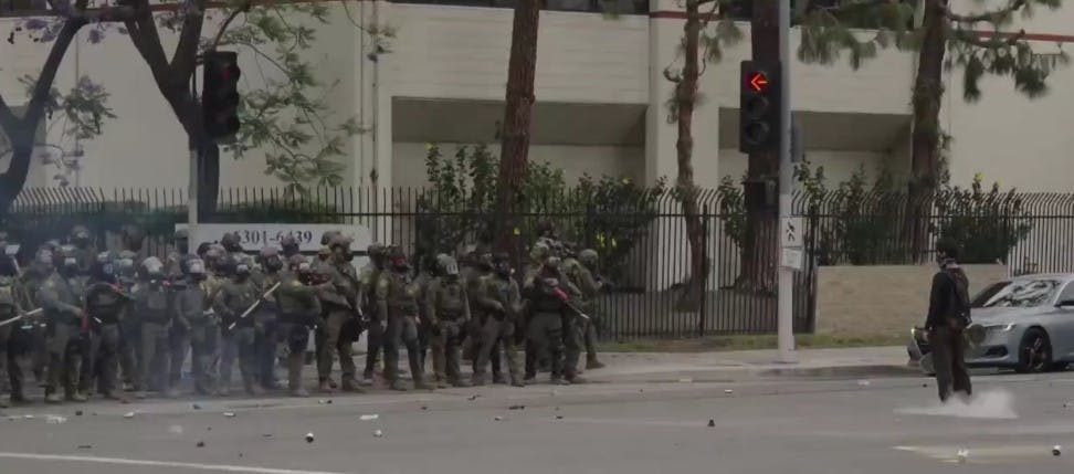 Szenerie aus Los Angeles, Dutzende Militarisierte Polizisten stehen einem Jugendlichen gegenüber