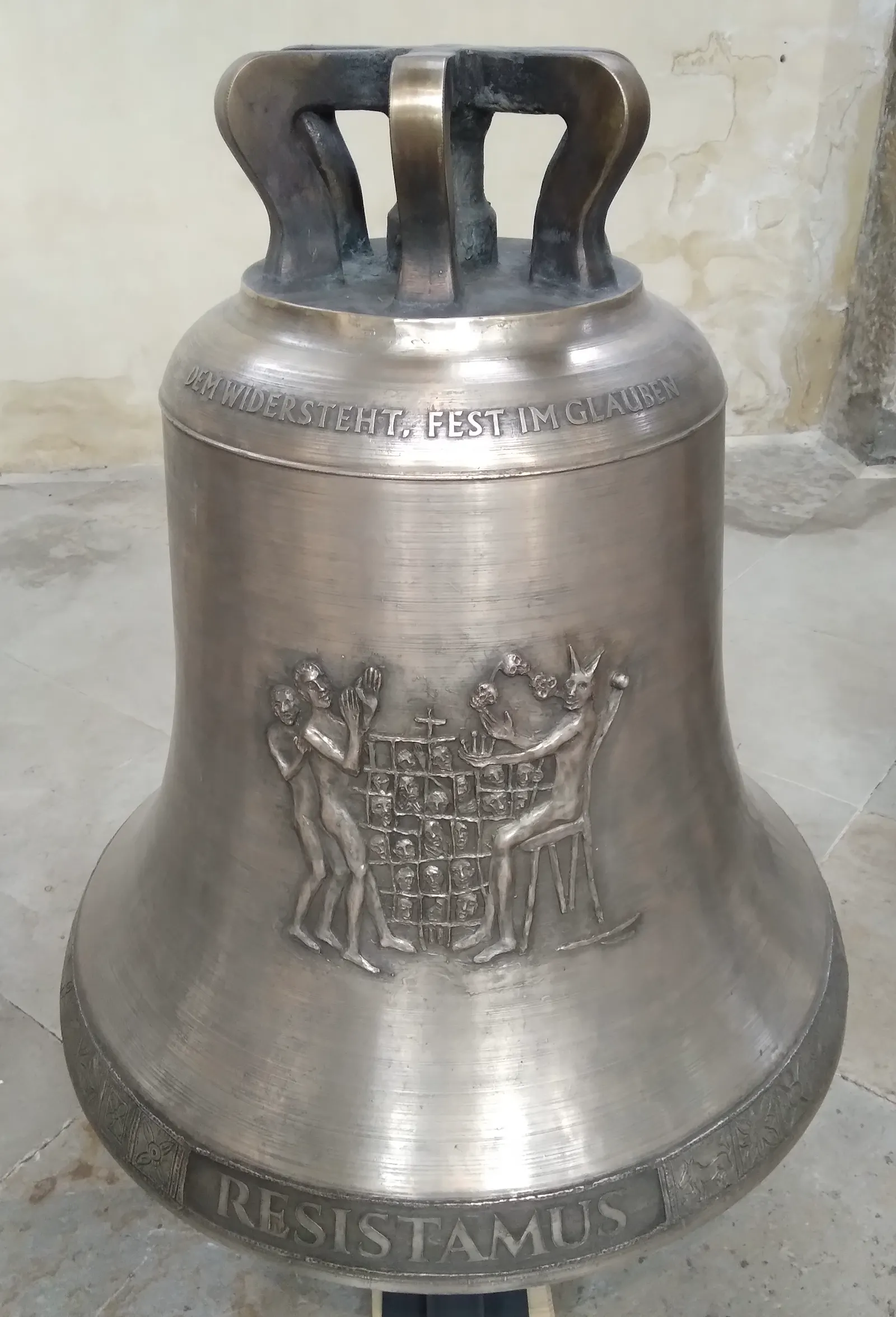 Eine glänzende Glocke steht auf dem Boden einer Kirche.