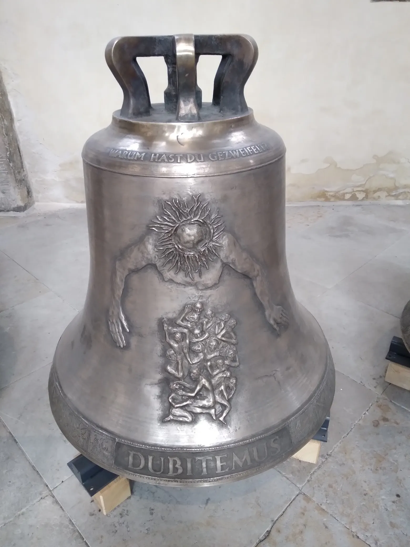 Eine Glocke steht auf dem Boden einer Kirche.