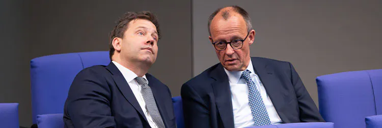 Lars Klingbeil und Friedrich Merz sitzen nebeneinander und reden.
