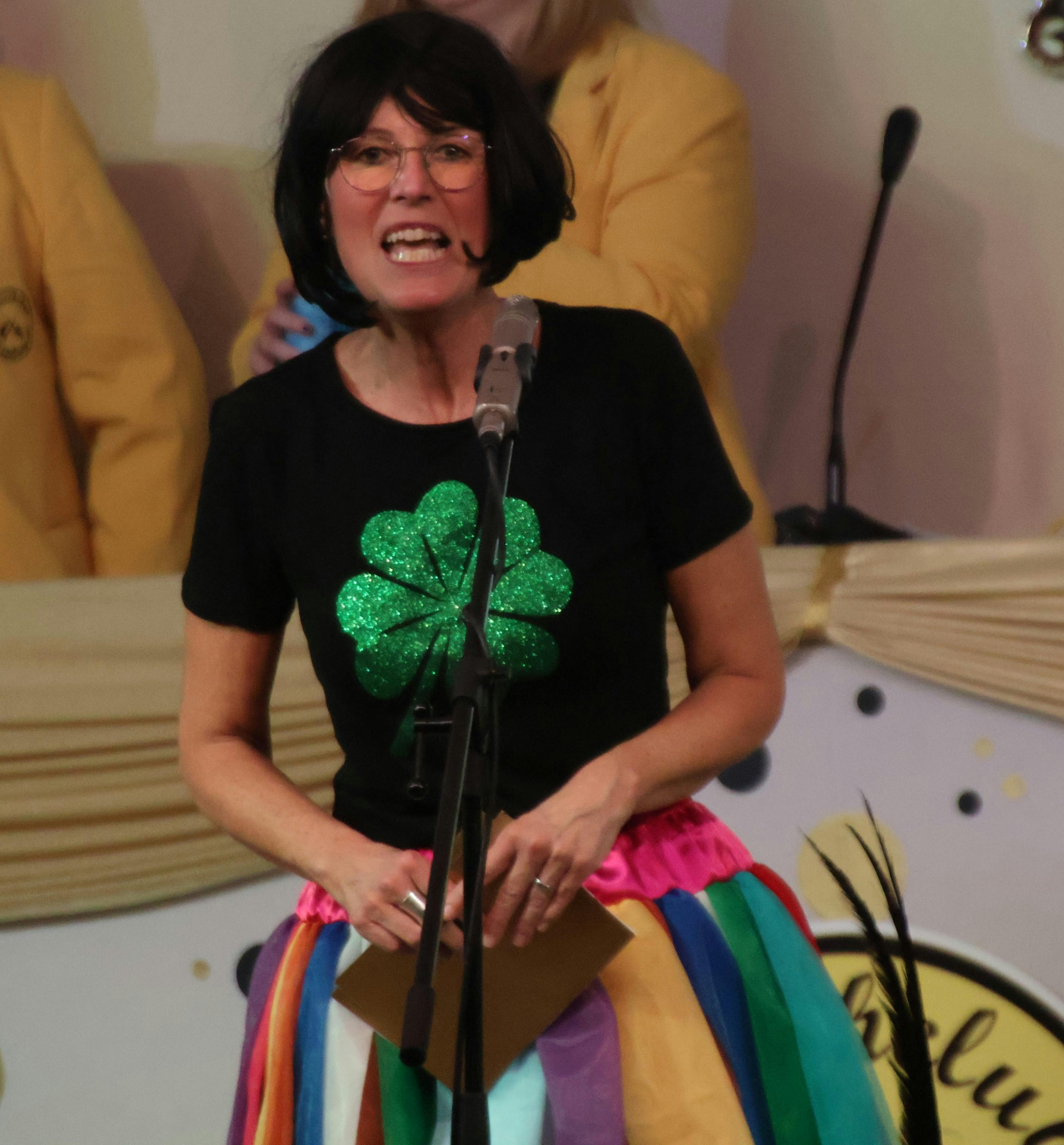 Frau mit schwarzer Perücke und einem schwarzen T-Shirt mit großem Kleeblatt bedankte sich nach der Kappensitzung für einen tollen Abend