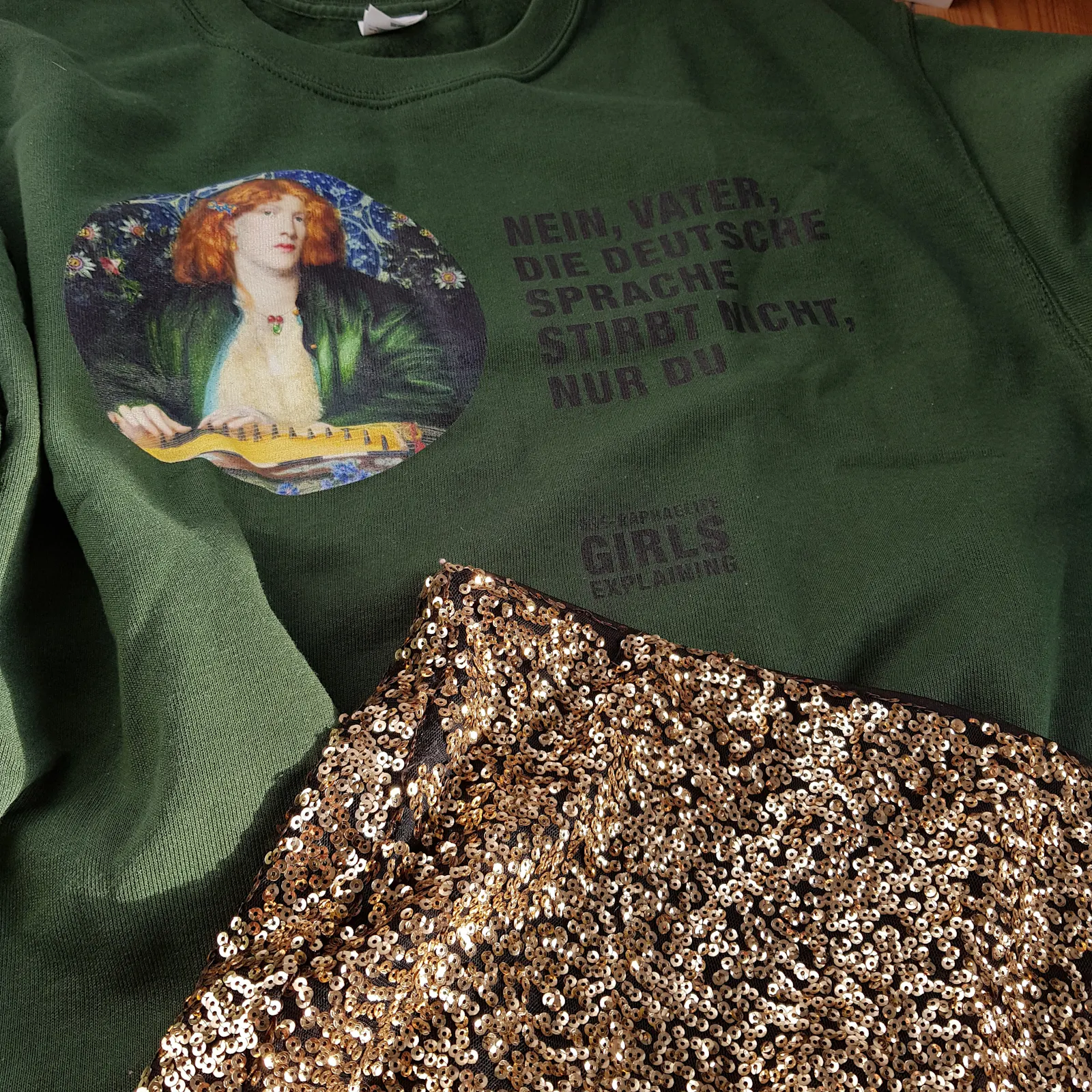 Waldgrüners Sweatshirt mit nachdenklich blickender rothaariger Gestalt und Text: NEIN, VATER, DIE DEUTSCHE SPRACHE STIRBT NICHT, NUR DU.