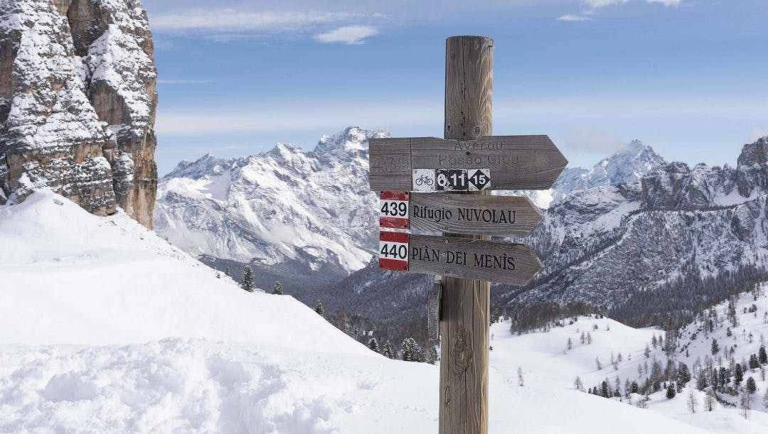 Un cartello in legno nella neve tra le montagne