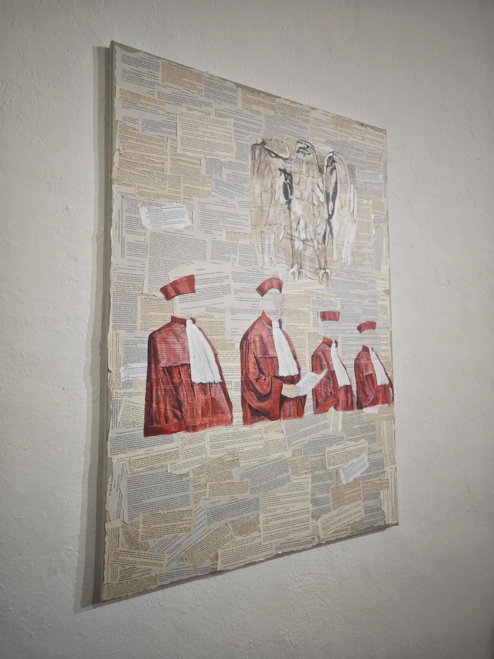 Eine Collage mit Texten auf Leinwand, im Vordergrund vier Bundesrichter in rot