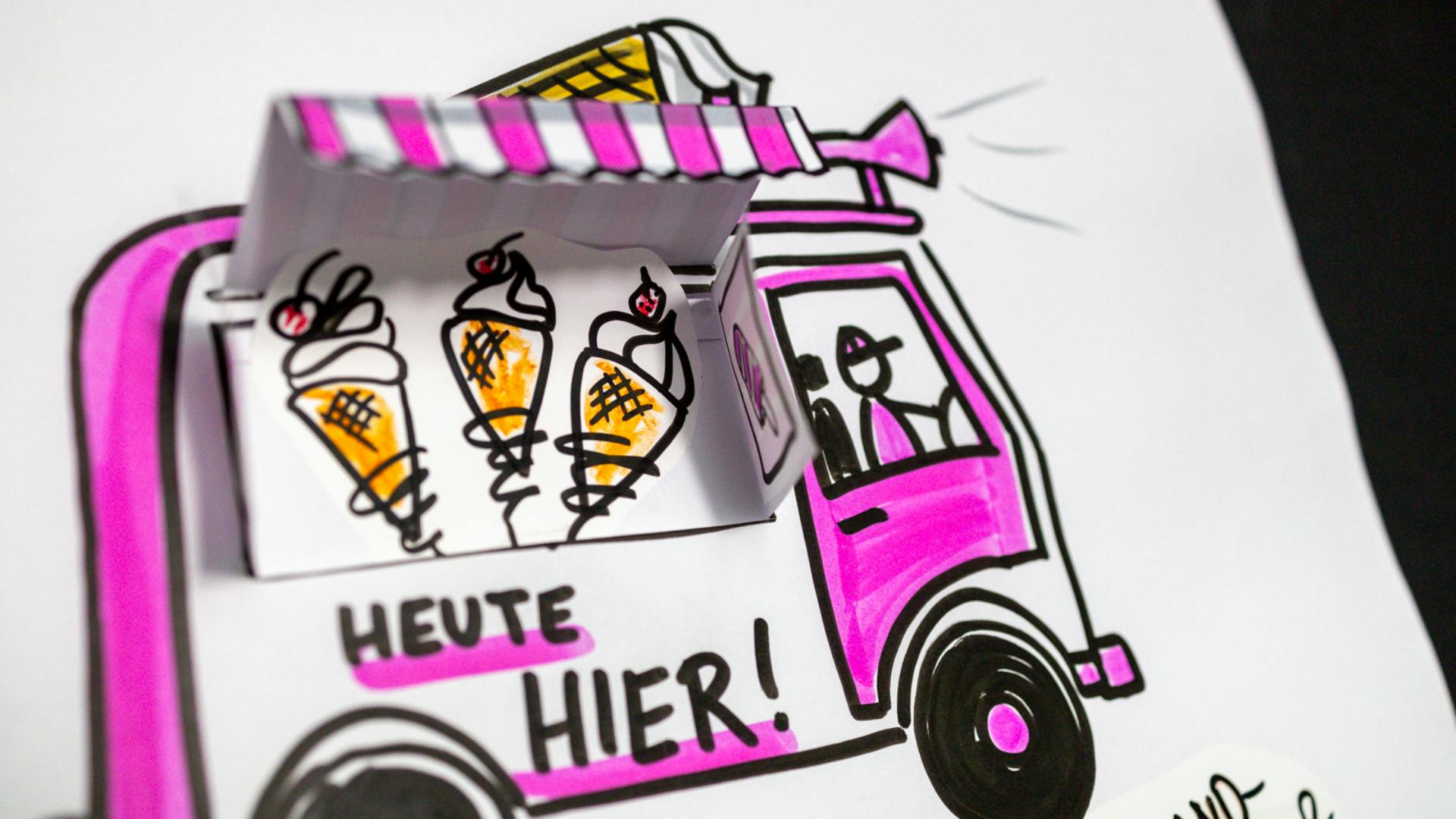 Eiswagen in den Farben pink und weiß mit einer seitlichen Markise, die aus Papier gebastelt und aufgeklappt ist.