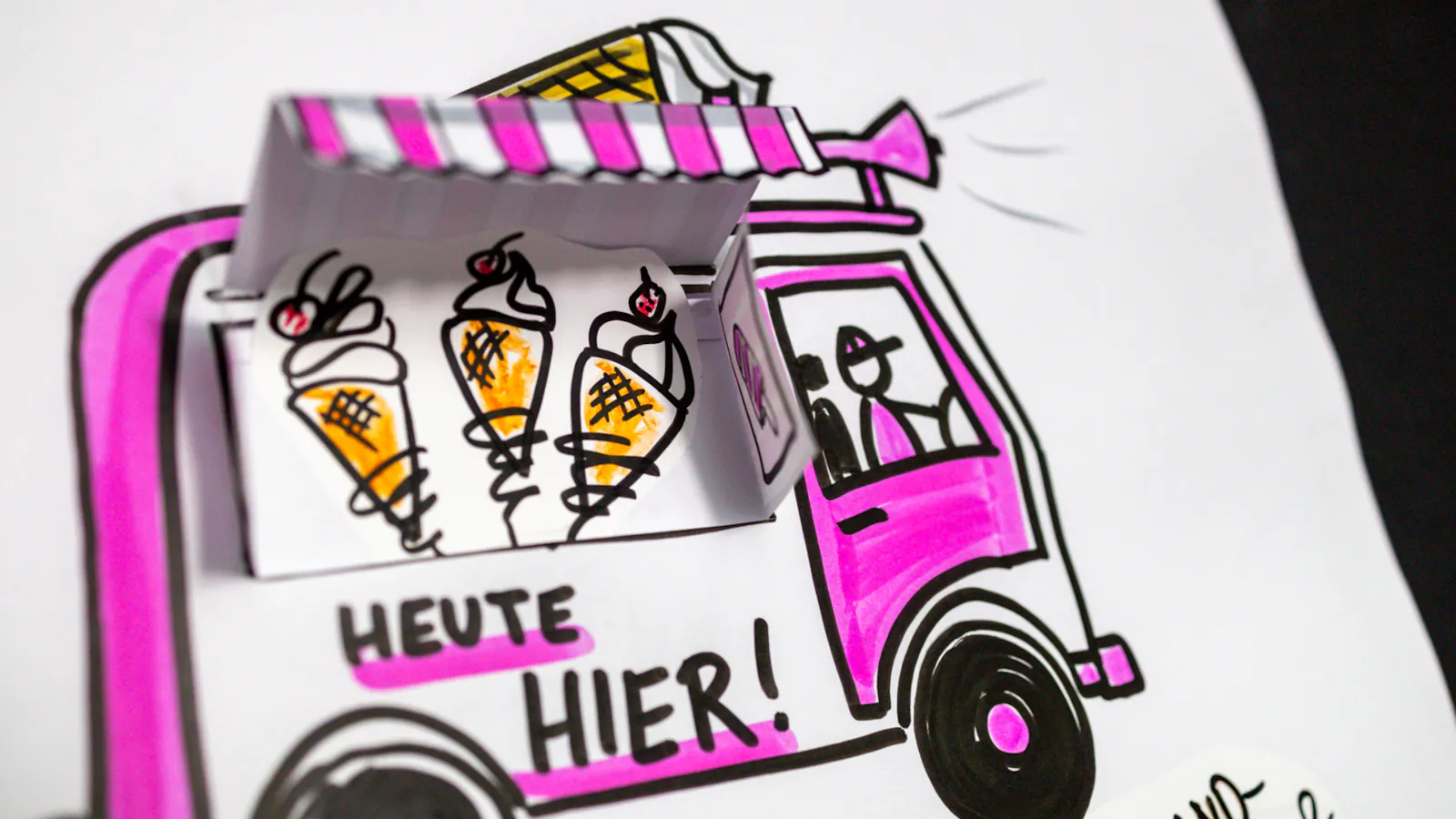 Eiswagen in den Farben pink und weiß mit einer seitlichen Markise, die aus Papier gebastelt und aufgeklappt ist.