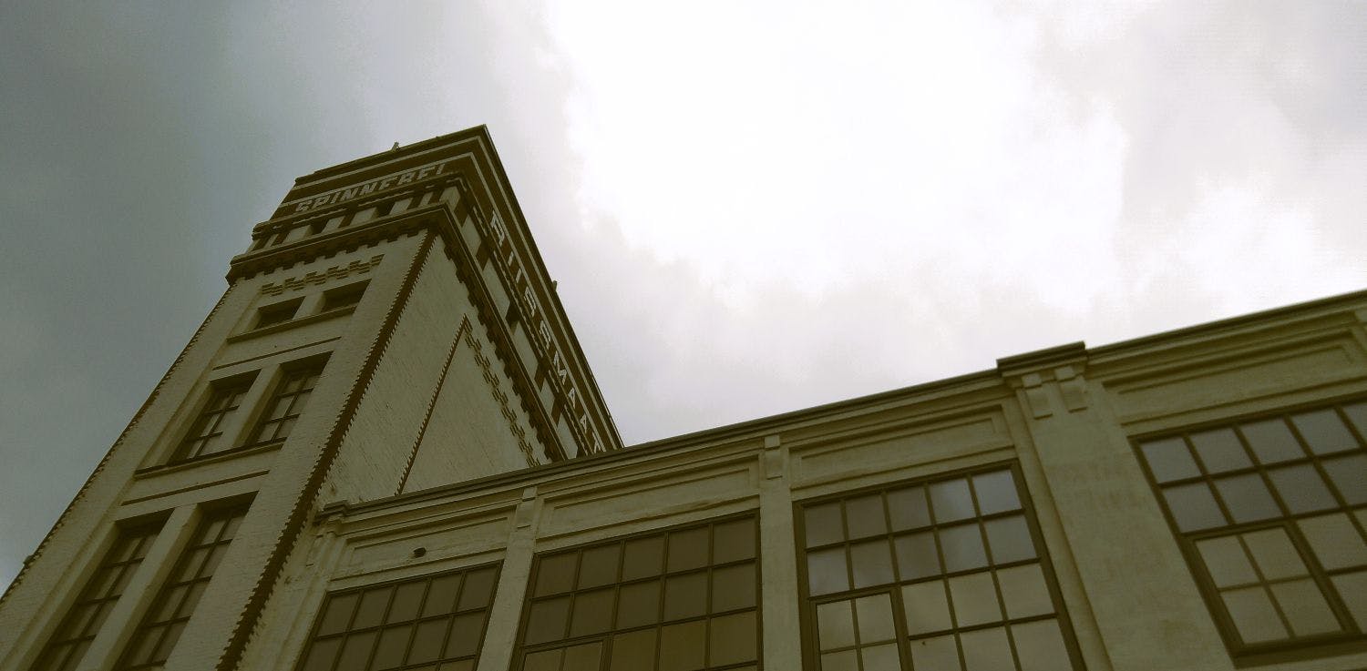 Ein Gebäude einer alten Fabrik von unten fotografiert, oben die Aufschrift Spinnerei.