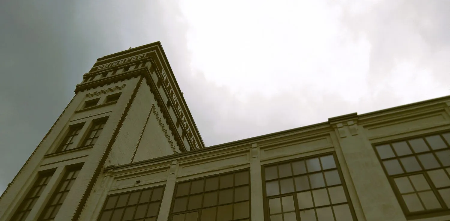 Ein Gebäude einer alten Fabrik von unten fotografiert, oben die Aufschrift Spinnerei.