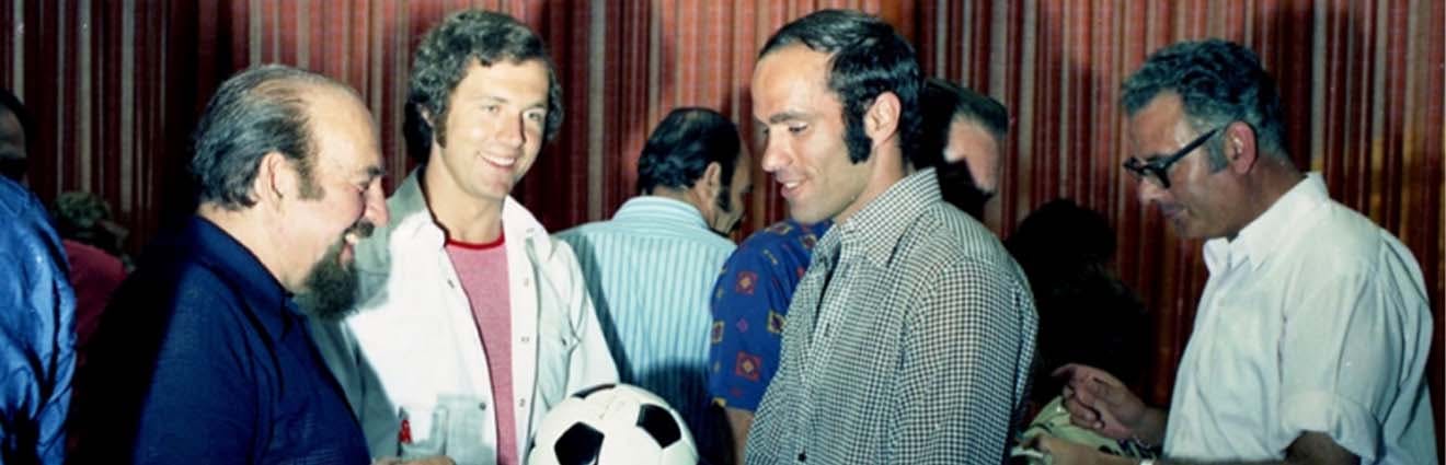 Yizchak Visoker, goal keeper of the Israeli national team, shaking hands with Franz Beckenbauer and giving a ball to Israeli actor Shmuel Rodensky, 1973