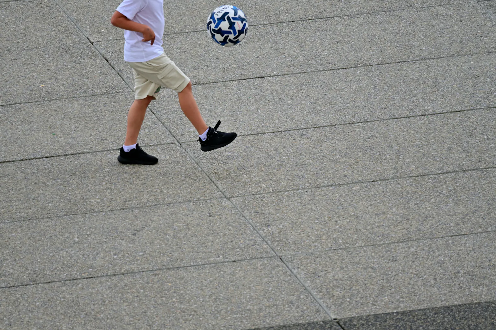 Foto von Amin Zabardast auf Unsplash: Bild von einem kleinen Jungen, der mit einem Fußball spielt.