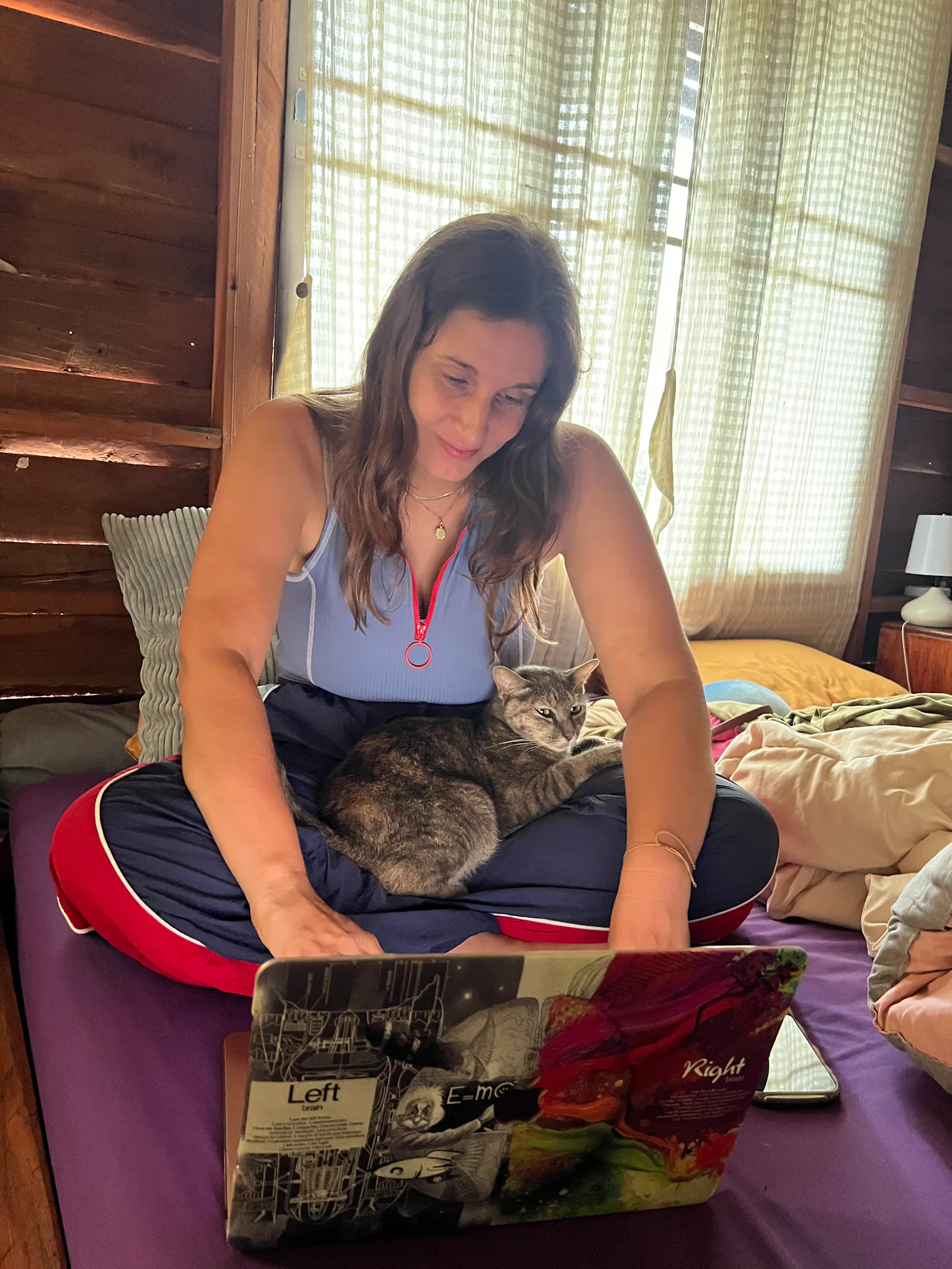 Josi sitzt im Schneidersitz vor ihrem Laptop und schreibt, eine Katze auf ihrem Schoß.
