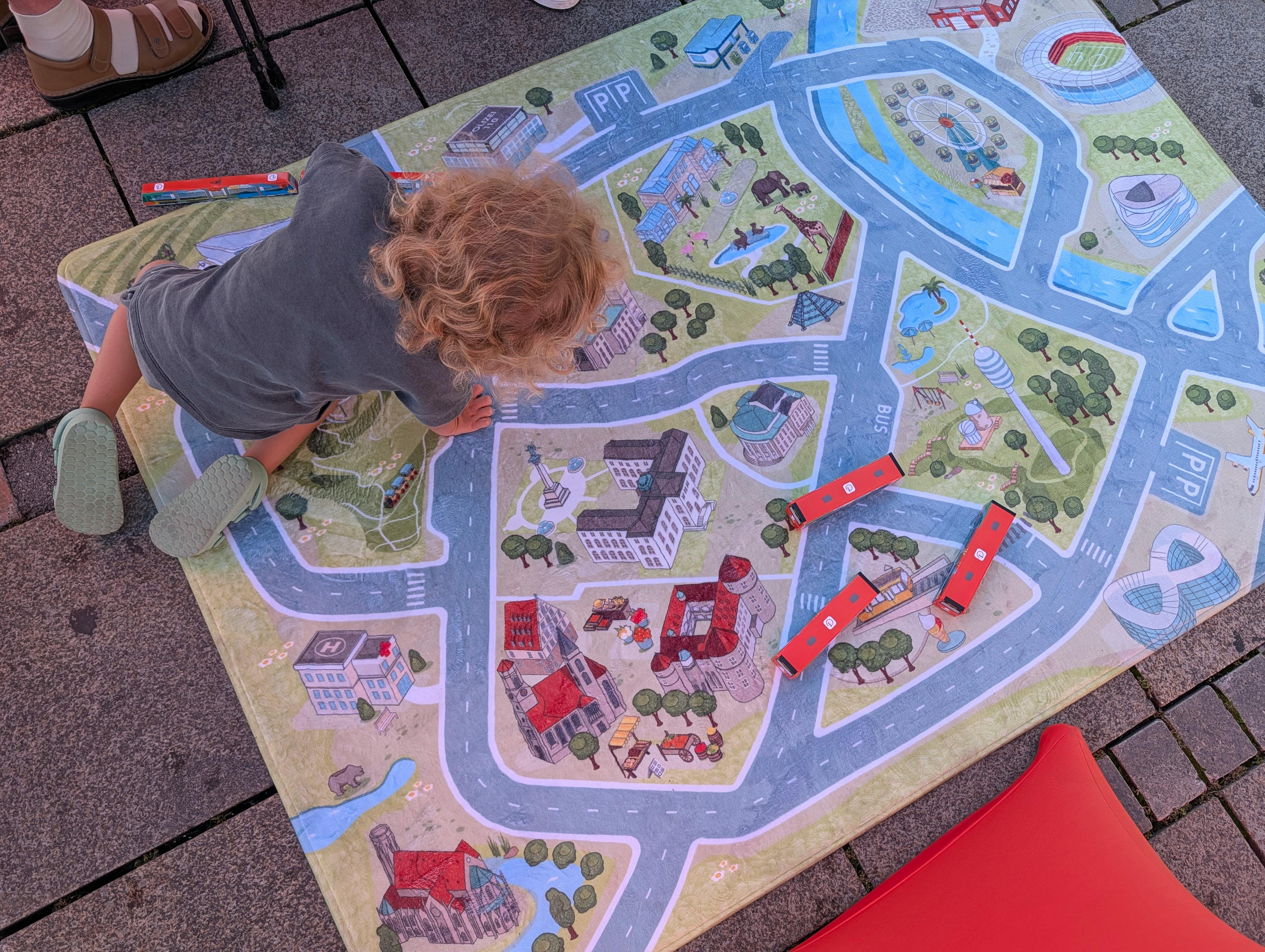 Ein Junge spielt mit selbst gefalteten Bussen und Bahnen auf dem Spieleteppich der VVS. Foto: Jürgen Brand