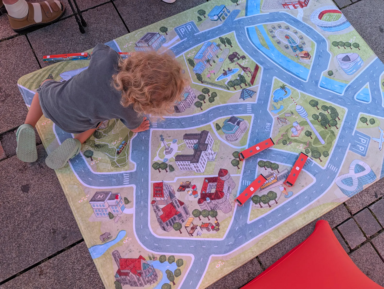 Ein Junge spielt mit selbst gefalteten Bussen und Bahnen auf dem Spieleteppich der VVS. Foto: Jürgen Brand