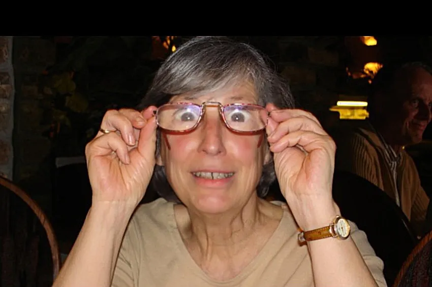 Christine Pionteks Mutter schaut humorvoll durch eine Brille, die ihre Augen stark vergrößert.