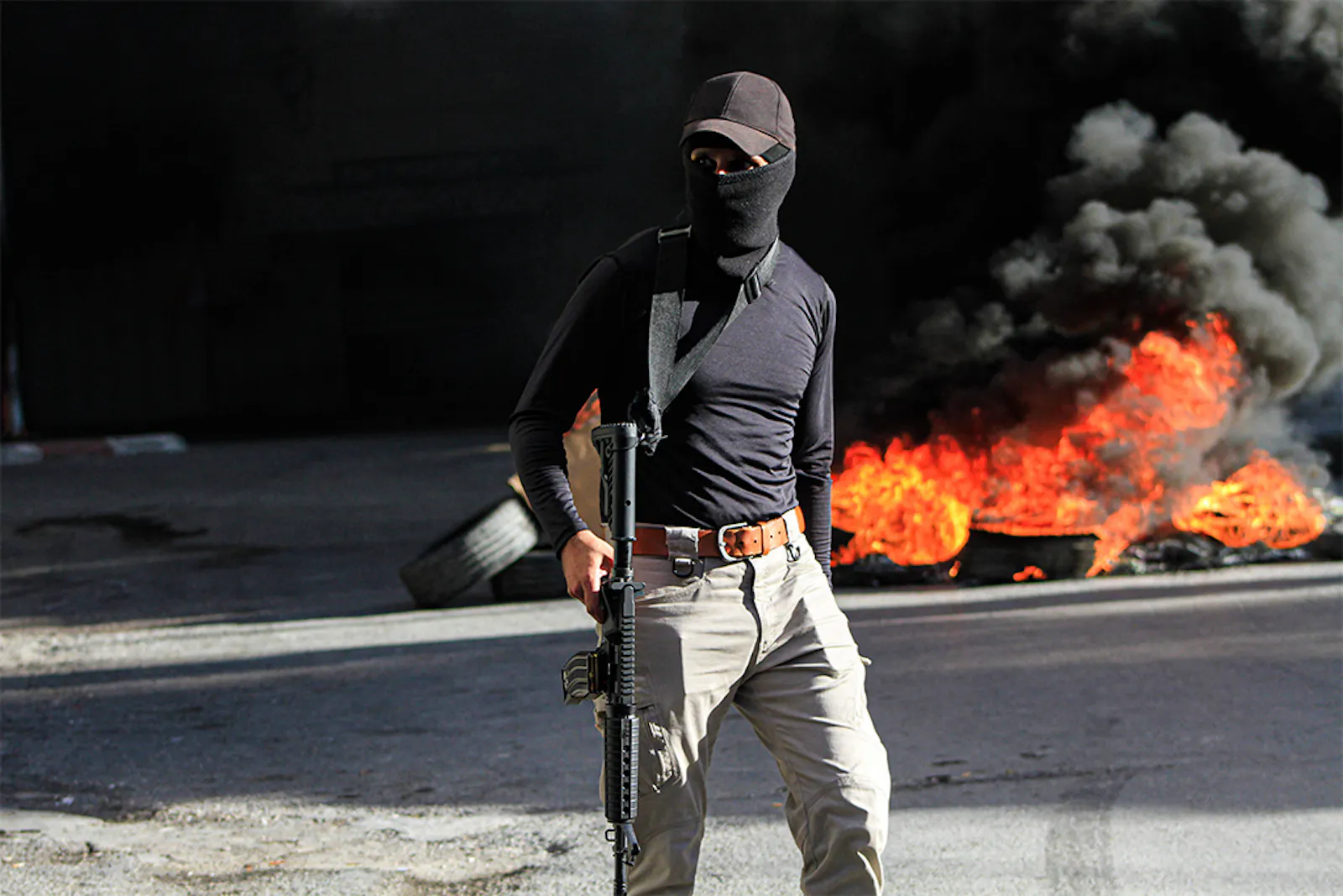 Palästinensischer Kämpfer vor brennenden Straßenbarrikaden