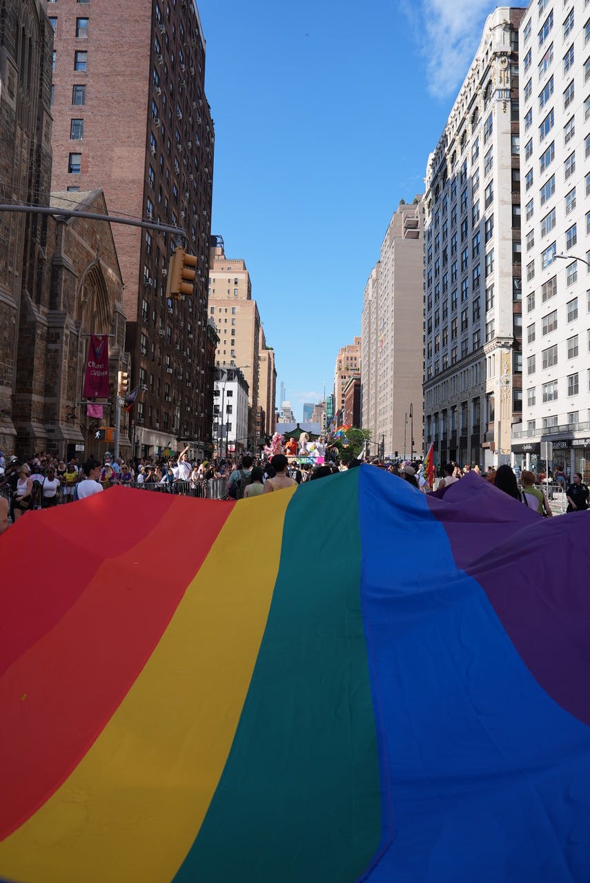 Riesige Regenbogenflagge bei der New York Pride 2025 in einer Häuserschlucht Manhattans