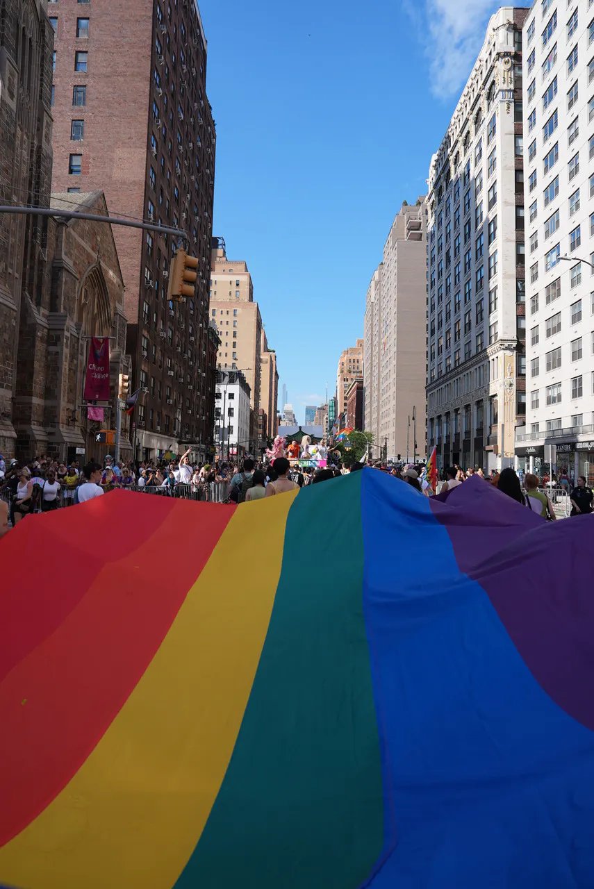 Riesige Regenbogenflagge bei der New York Pride 2025 in einer Häuserschlucht Manhattans