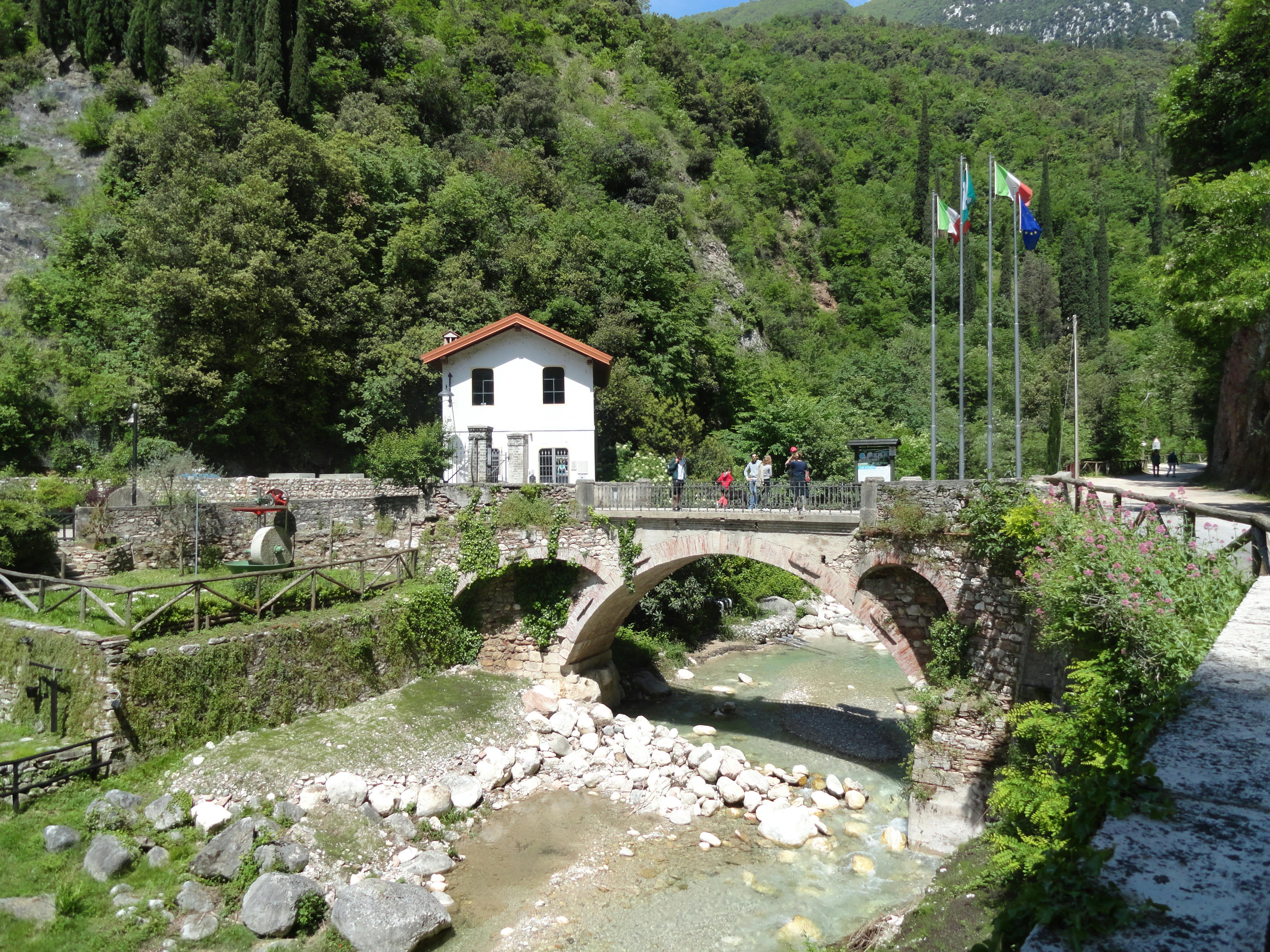 Haus vor einer grün bewachsenen Felswand mit einem Fluss davor
