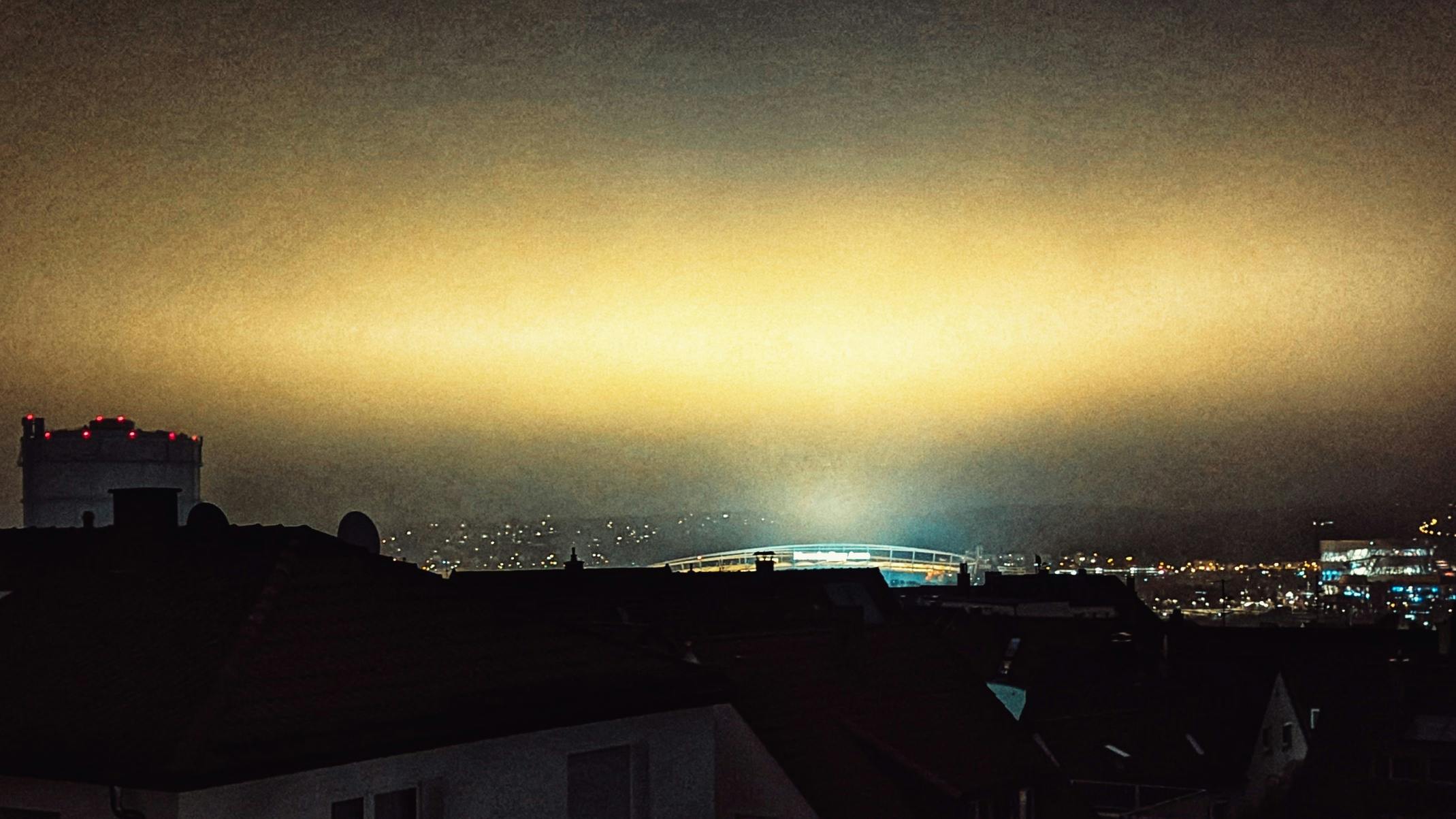 Symbolbild: Lichtschein über der Mercedes-Benz-Arena bei Nacht, links der Gaskessel, rechts das Mercedes-Benz-Museum. Foto: Jürgen Brand