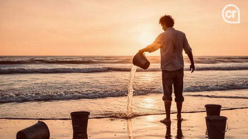 Ein Mann steht am Ufer des Meeres und schüttet Wasser in das Meer. Stimmung Sonnenuntergang