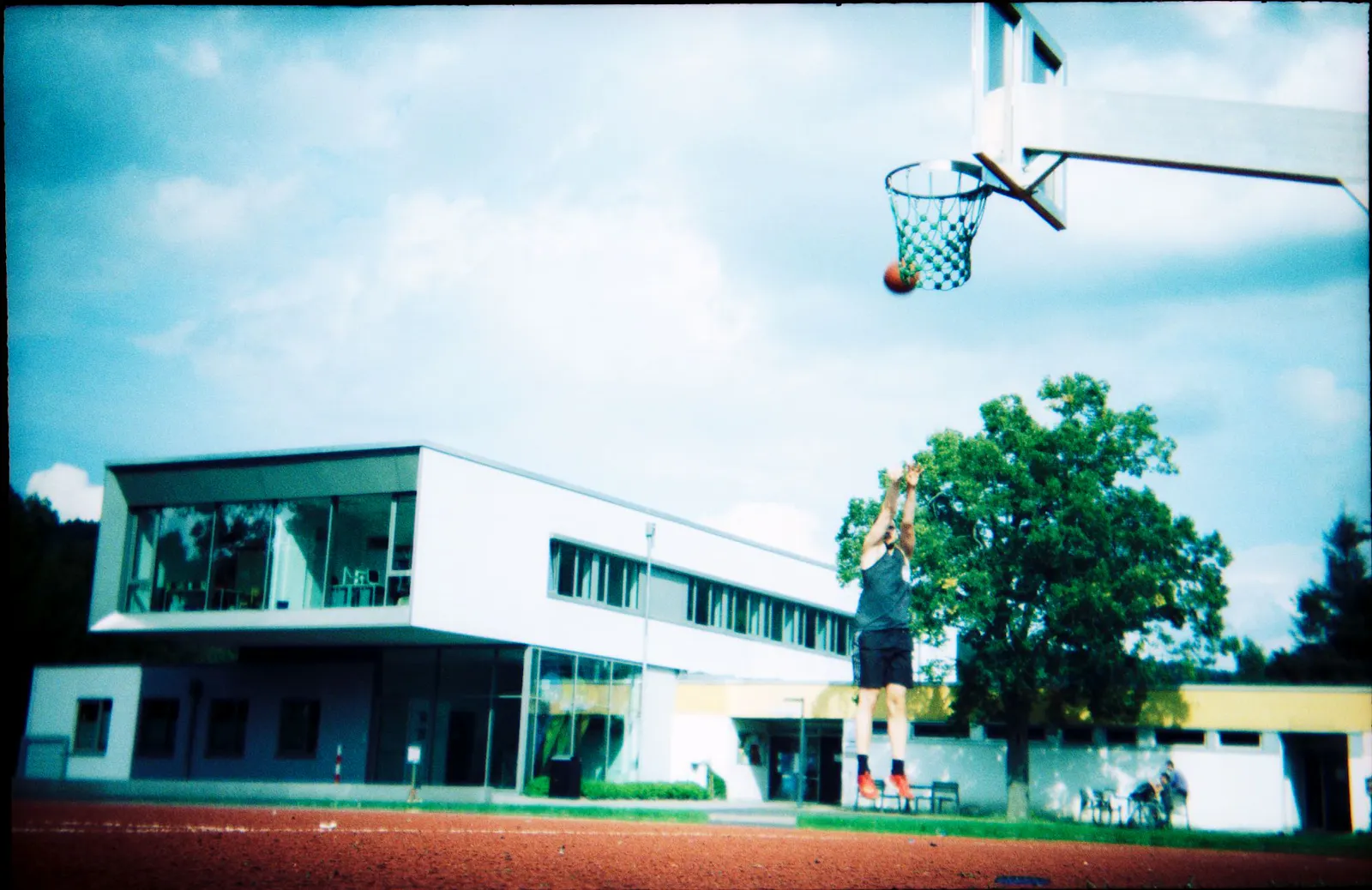 Eine Fotografie von einem Basketballspieler, der springend den Ball in Richtung Korb wirft.