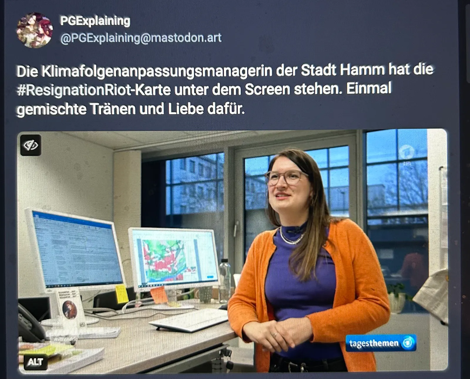 Screenshot aus den Tagesthemen. Person steht vor Computerscreen, unten erkennbar PGExplaining-Postkarte mit »Resignation ... riot ... resignation ... riot ...«