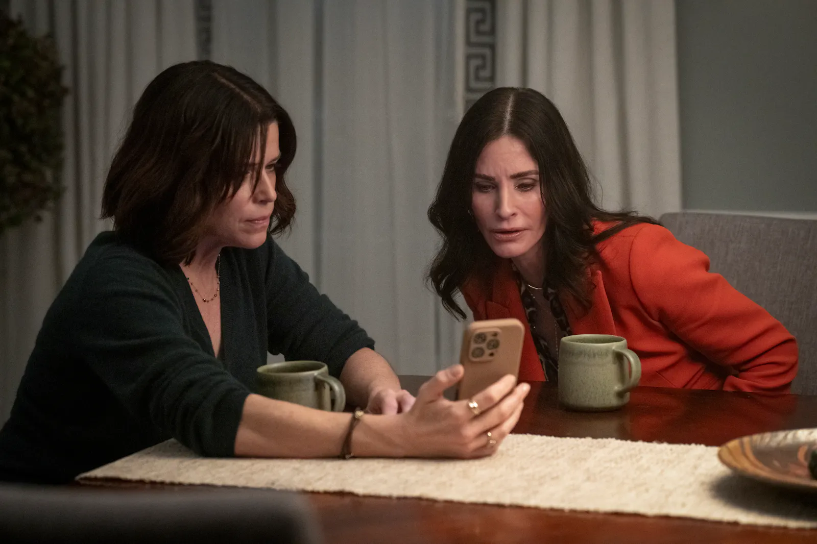 Frenemies?! Sidney (Neve Campbell) und Gale (Courteney Cox) in SCREAM 7 am Tisch mit Tee, sie schauen gemeinsam auf Sidneys Handy// Foto von: Jessica Miglio © 2025 PARAMOUNT PICTURES. ALL RIGHTS RESERVED.