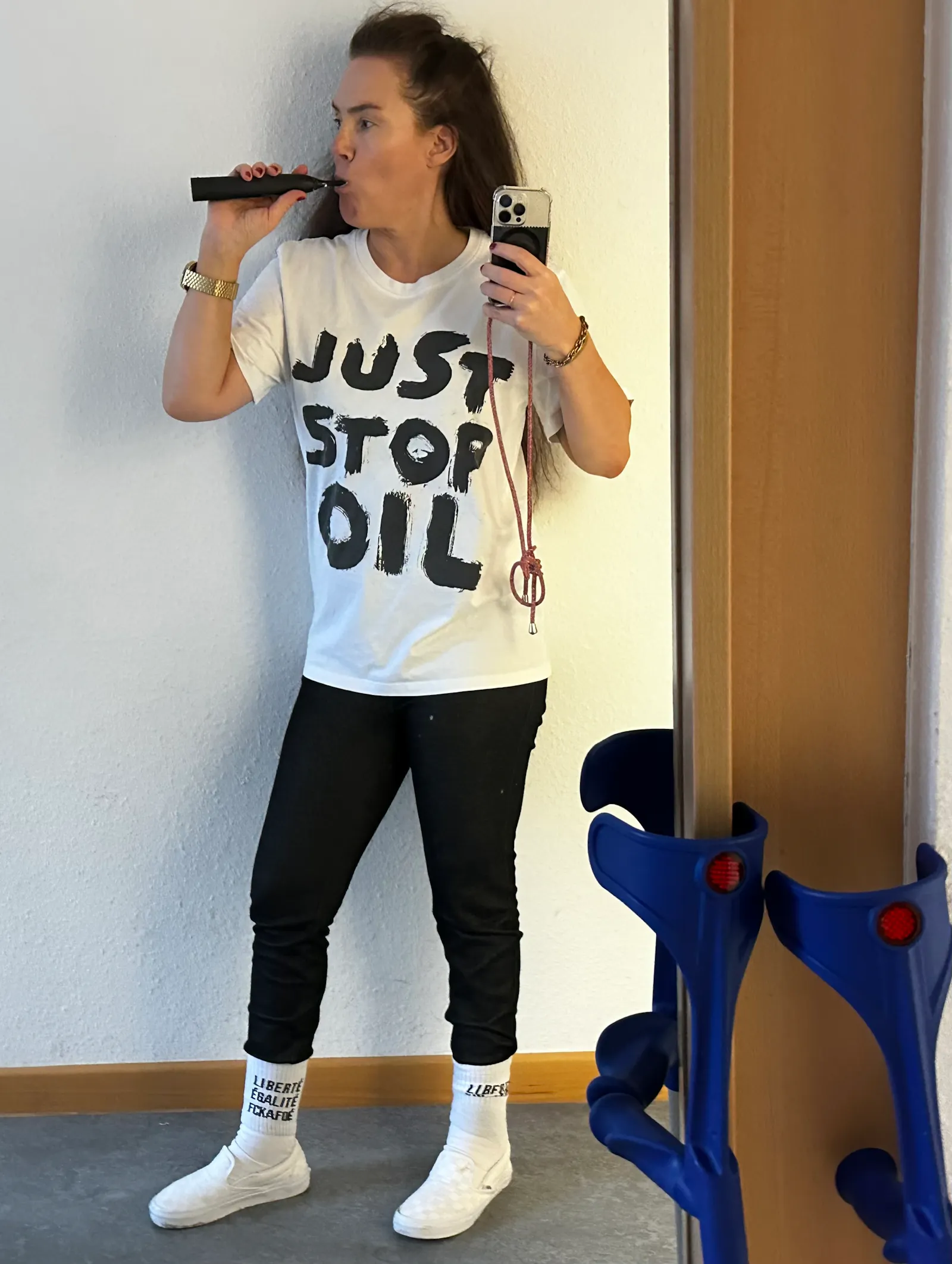 Ich putze mir vor einem Spiegel die Zähne und trage ein weißes Shirt mit "Just stop oil" sowie Socken mit "Egalité, Fraternité, FCKAFD",