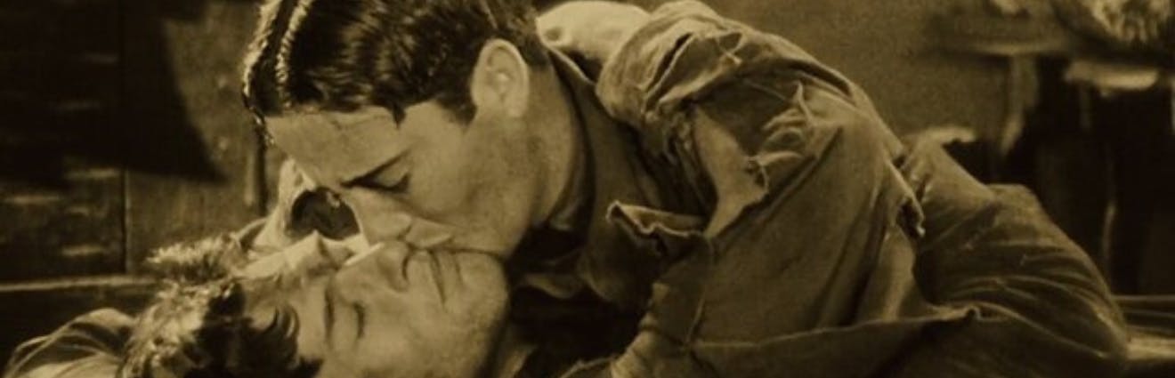 Screenshot aus dem Film Woke zeigt einen Mann über einen anderen gebeugt, ihn küssend